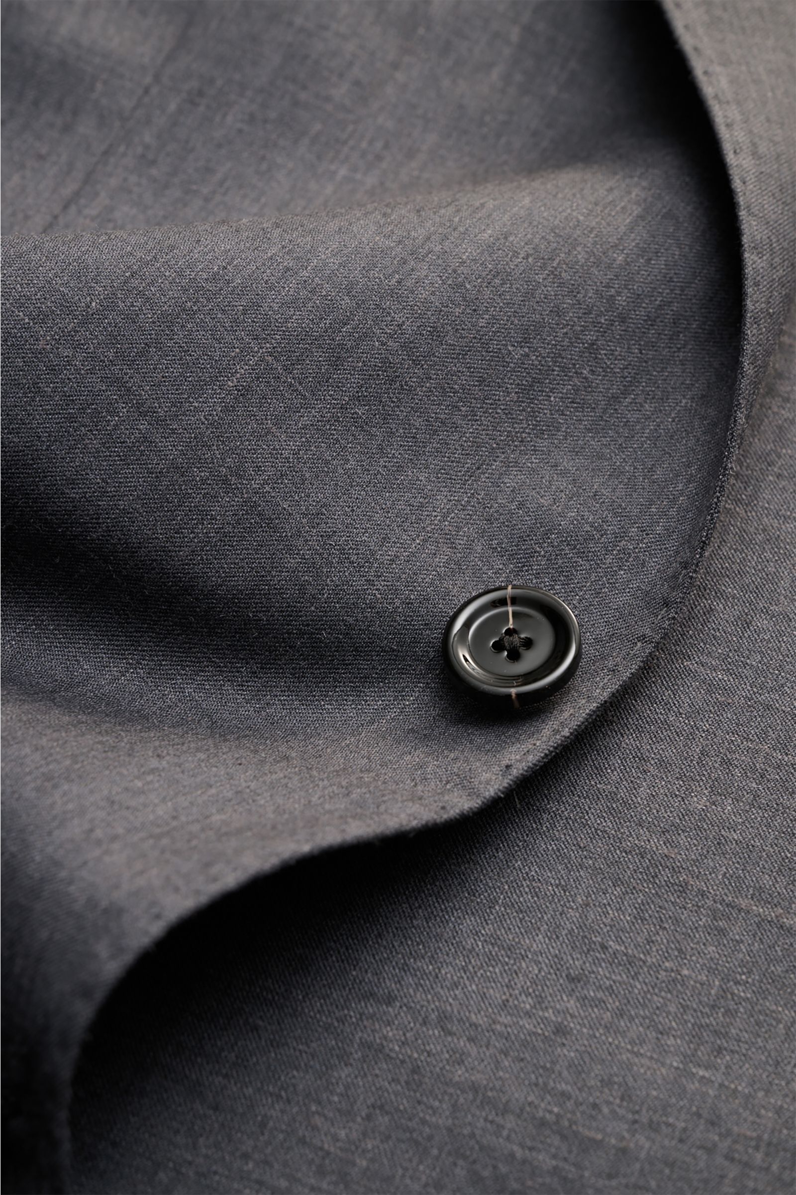 Detailaufnahme des Lardini Sakko dunkelgrau meliert mit Fokus auf Knopf und feiner Wolle-Seide-Leinen-Mischung aus schräger Perspektive.