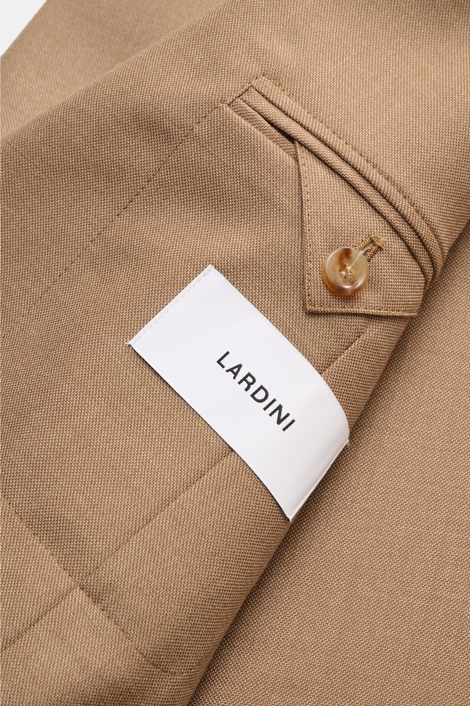 Lardini Cashmere Sakko hellbraun in Nahaufnahme von innen, zeigt weichen Griff, Slim Fit, fallendes Revers mit Blüten-Anstecker, Zwei-Knopf-Stil, Brust- und Hüfttaschen, Ärmel mit Knopf, Seitenschlitze, unconstructed Design und zwei Innentaschen. Verarbei