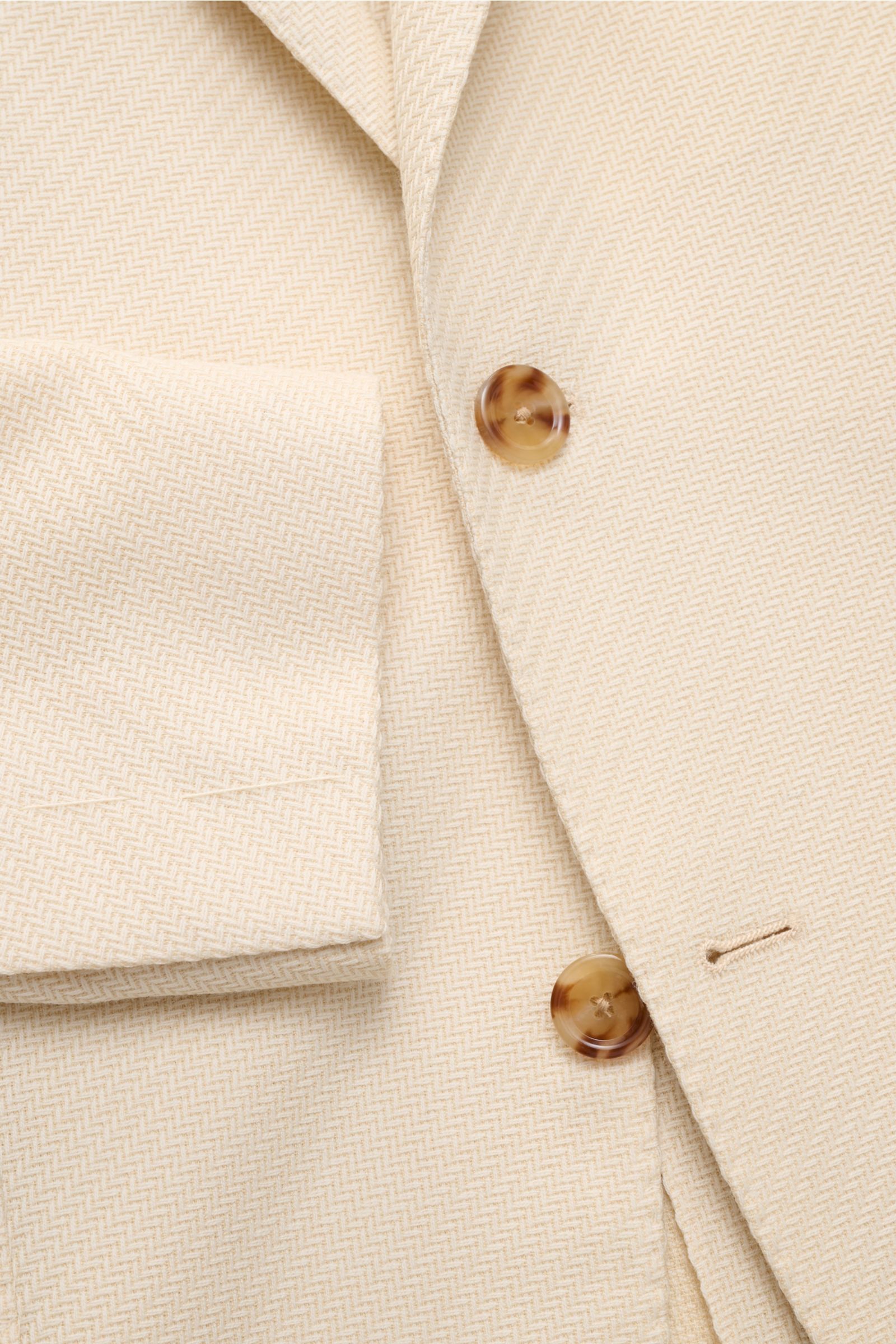 Close-up front view of Lardini Smart-casual jacket cream showing tonal herringbone pattern, two tortoiseshell buttons, step lapel with flower pin, and cuff detail. 

An Italian design classic: This smart-casual jacket from LARDINI made of wool and cott