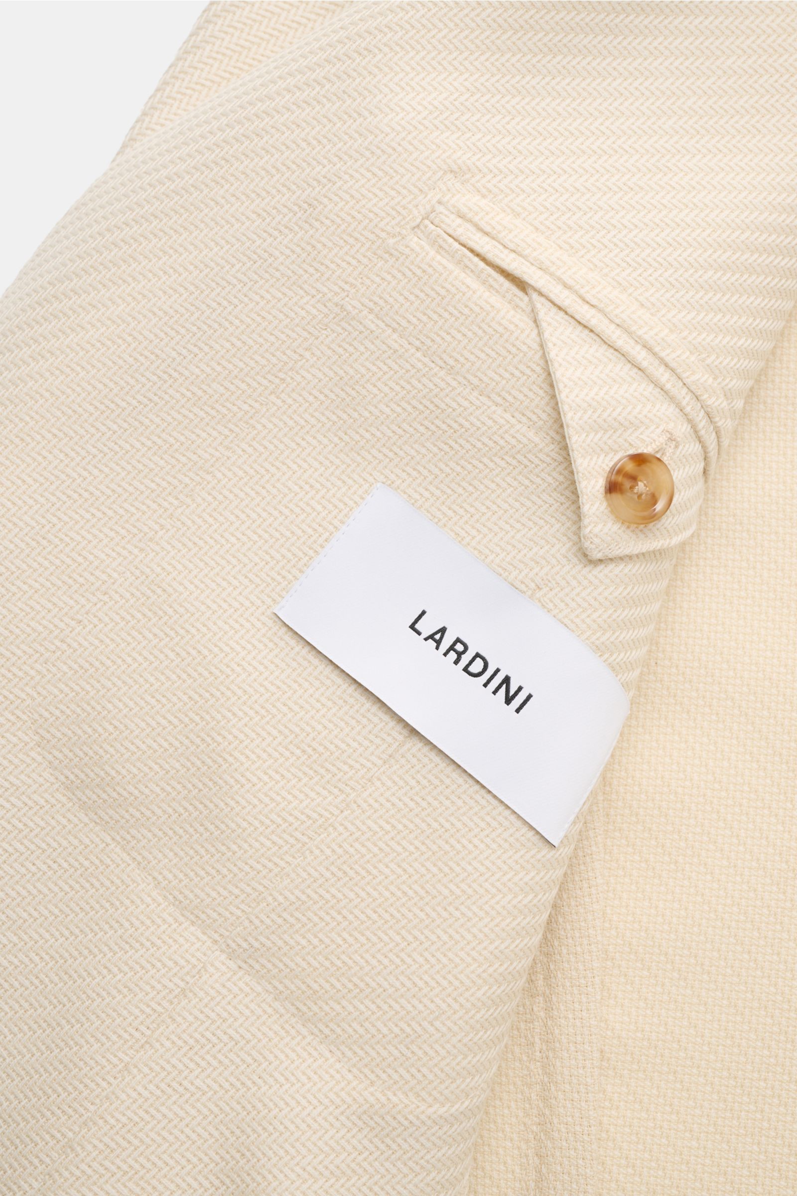 Close-up of the inside of the Lardini Smart-casual jacket cream, showing the tonal herringbone pattern, buttoned cuff detail, and Lardini label.

An Italian design classic: This smart-casual jacket from LARDINI made of wool and cotton features an inter