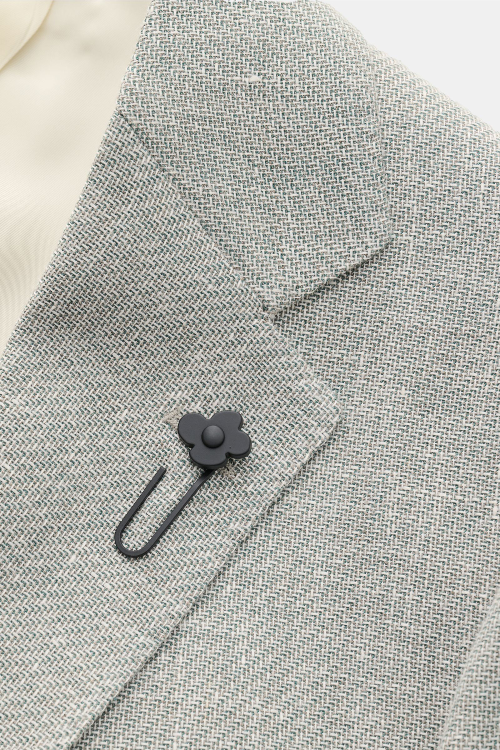 Lardini Sakko salbei/offwhite meliert, Detailaufnahme von Revers mit schwarzem Blüten-Anstecker, feine Schurwolle-Leinen-Webstruktur.