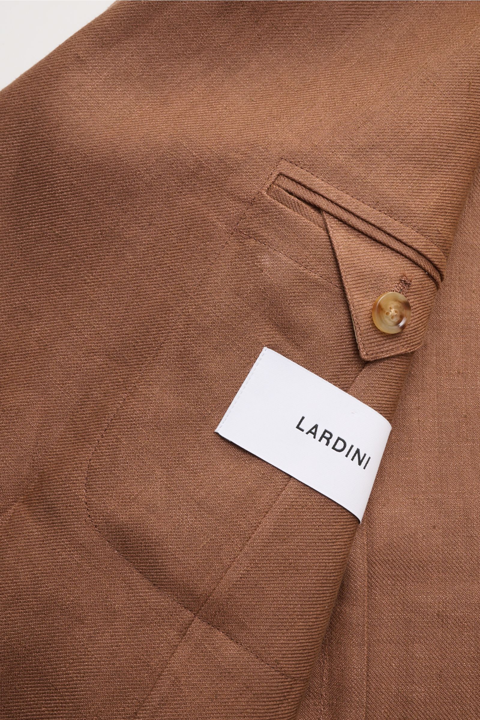 Close-up front view of Lardini Linen jacket brown showing patch hip pocket, buttoned unfinished sleeve cuff, and fabric texture.

Description: Airy and elegant: This double-breasted smart-casual jacket made of linen by LARDINI is the best choice when i