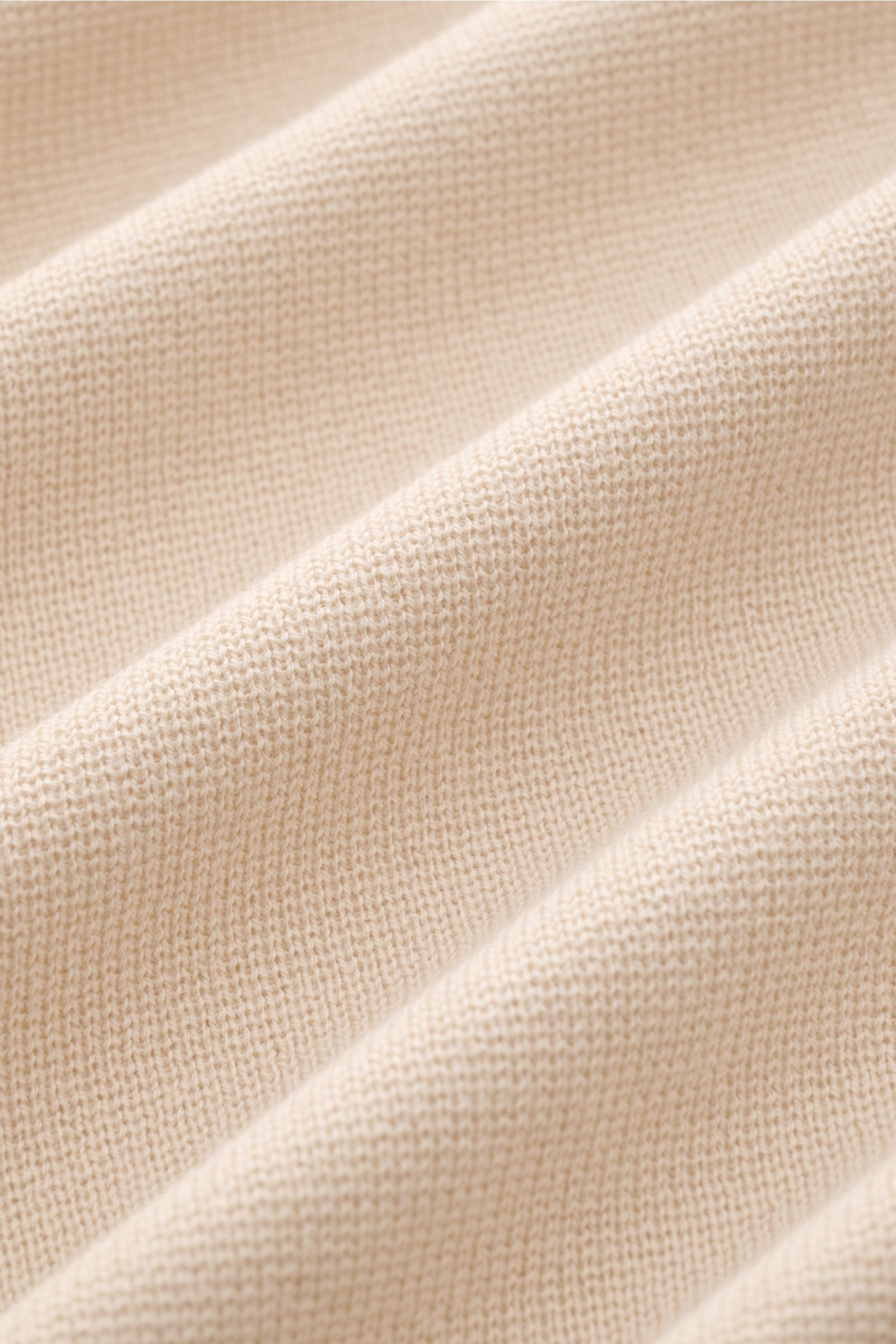 Nahaufnahme des feinen, glatten Strickbilds eines cremefarbenen Lardini Strickblazers aus reiner Baumwolle mit weichem Griff.