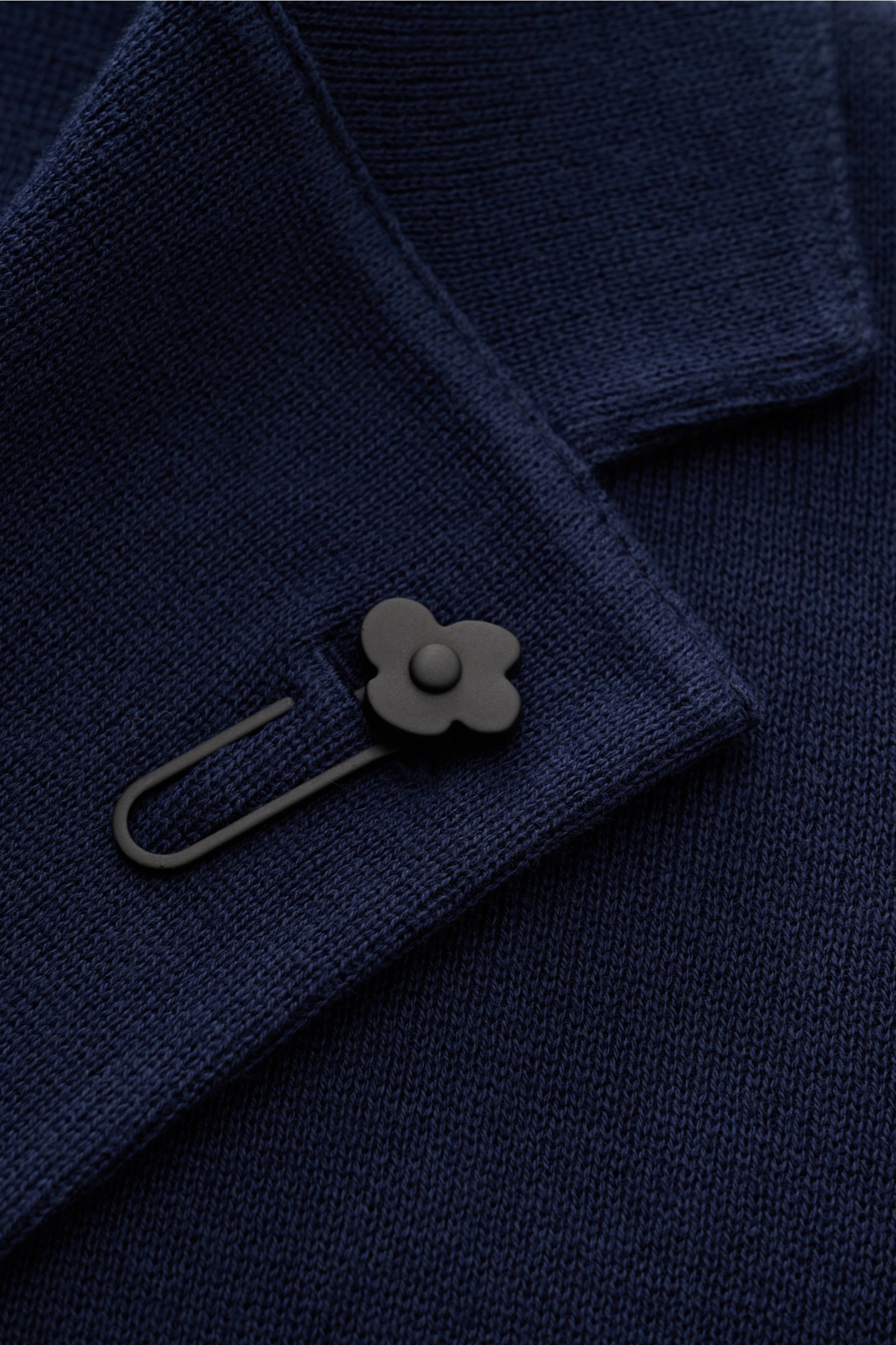 Nahaufnahme des fallenden Revers mit schwarzem Blüten-Anstecker am Lardini Strickblazer navy aus feinem Baumwollstrick.