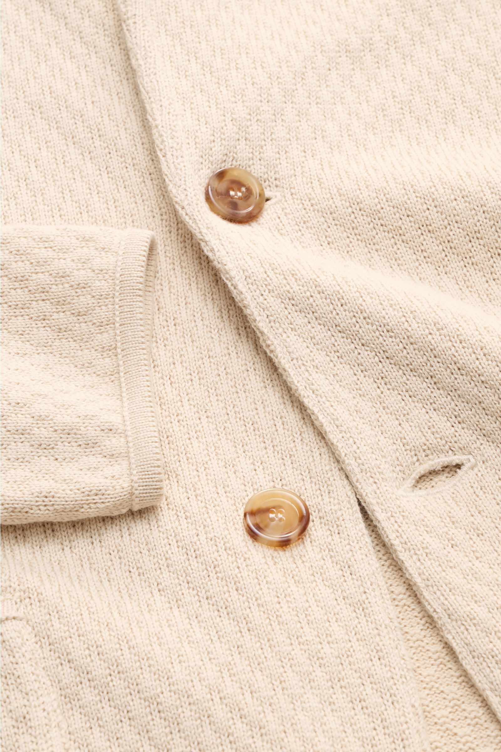 Lardini Strickblazer beige in Nahaufnahme, Detail von Knöpfen, markantem Strickmuster und geripptem Ärmelbündchen aus reiner Baumwolle.