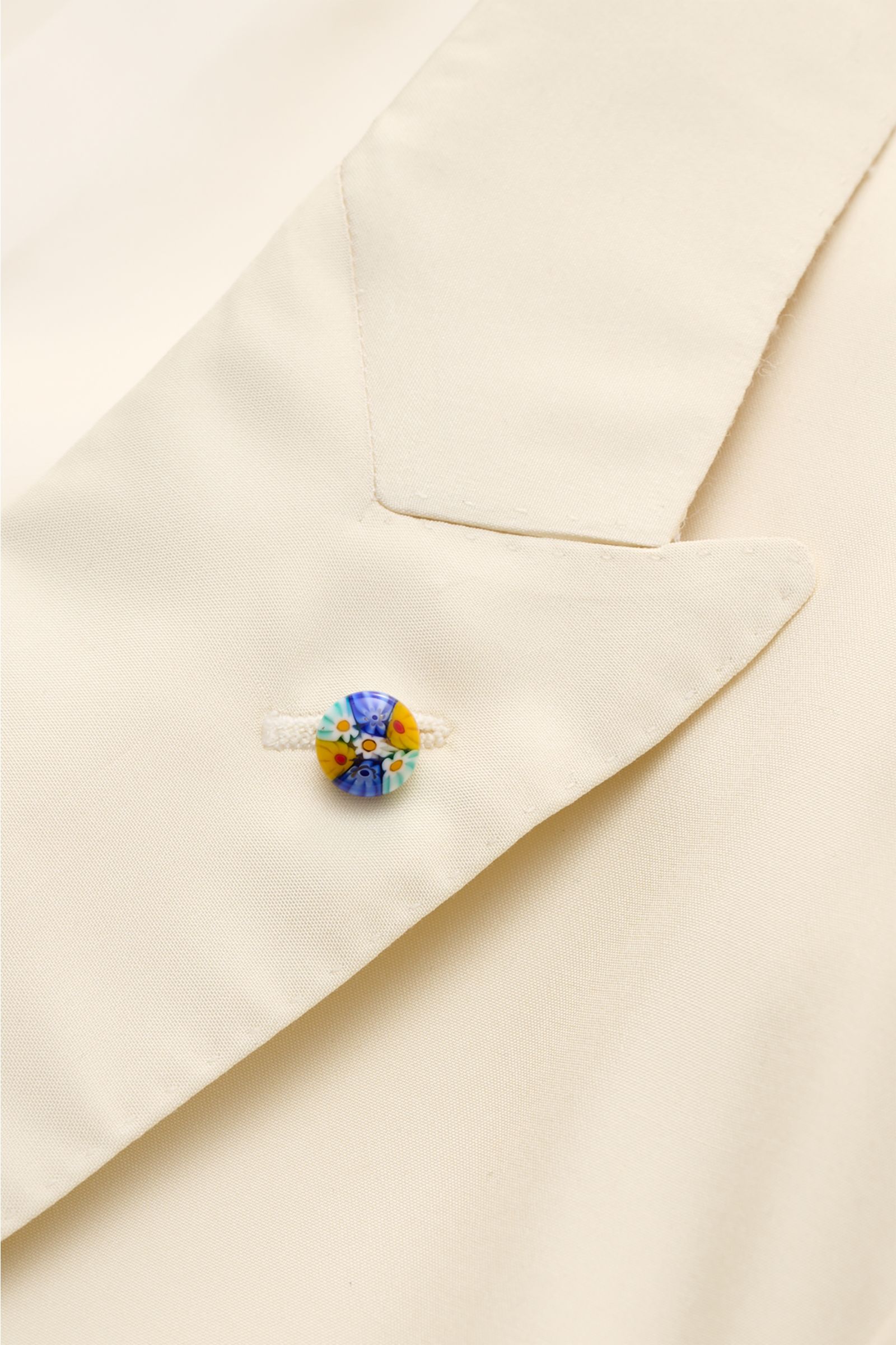 Belvest Seiden-Sakko creme in Nahaufnahme von schräg oben, mit glattem Griff, Spitzrevers, Perlmuttknopf und hochwertiger Seidenstruktur.