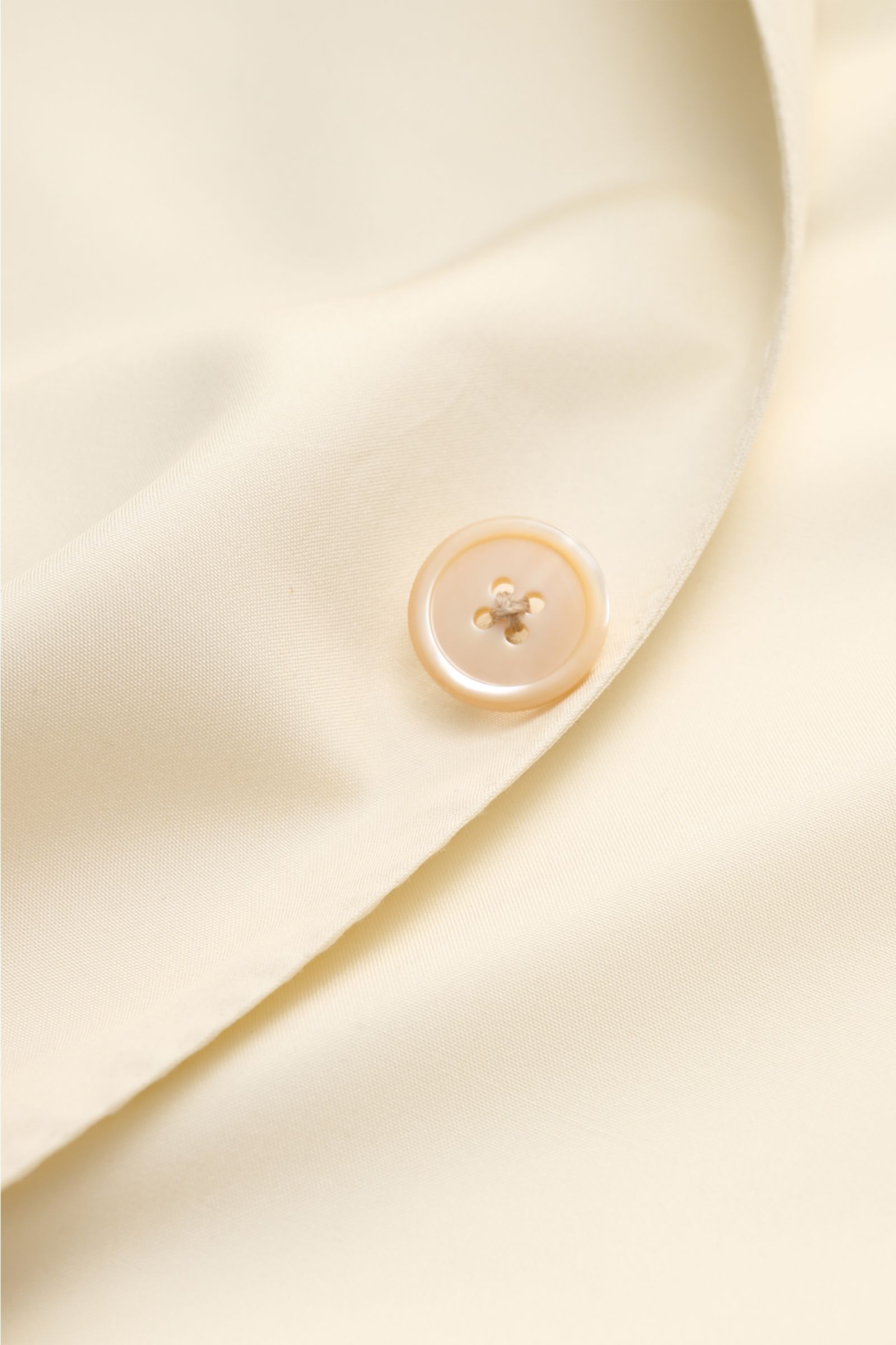 Nahaufnahme des Belvest Seiden-Sakko creme mit Perlmuttknopf, glattem Griff und Spitzrevers, seitliche Perspektive.