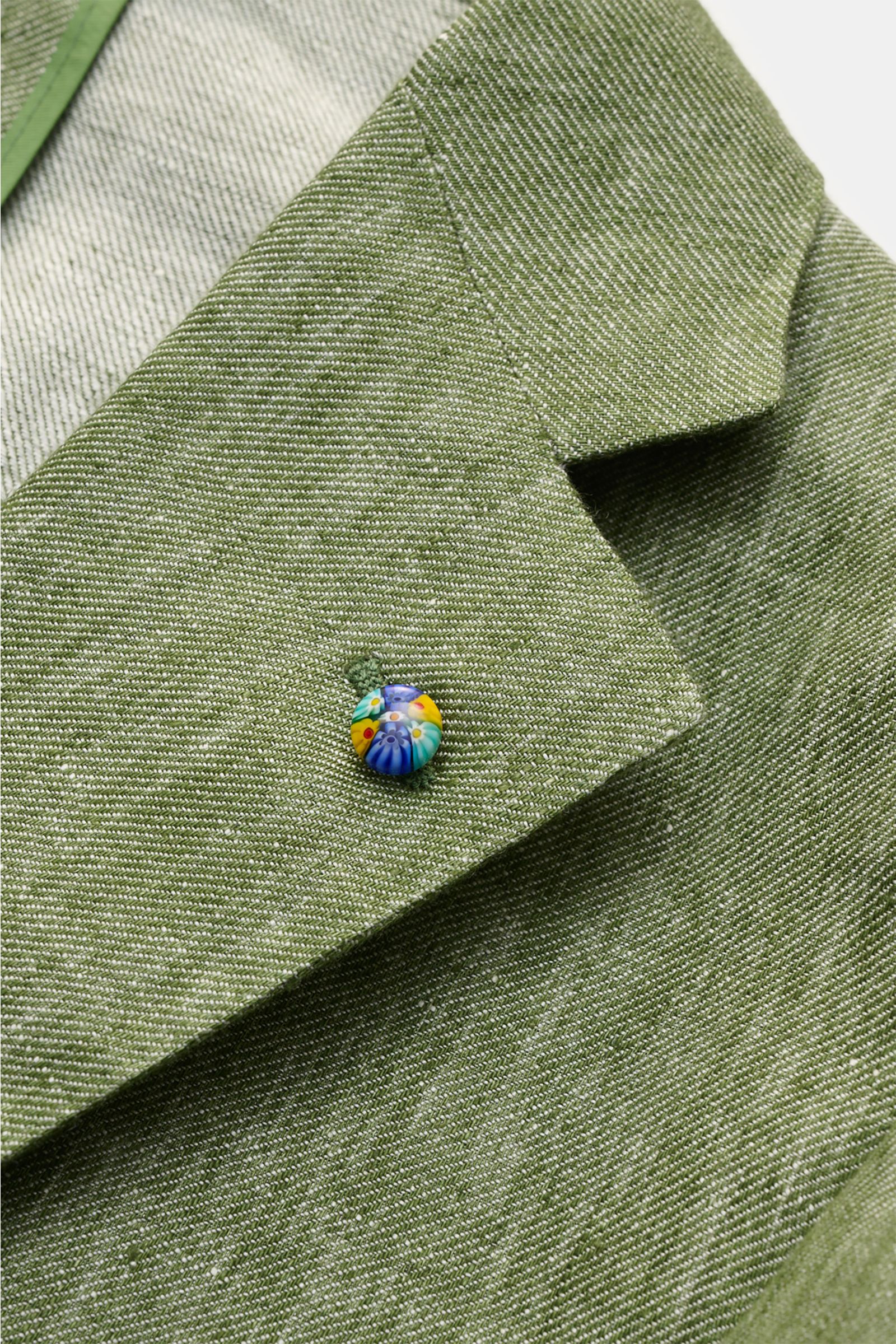 Belvest Leinensakko grün meliert, Detailaufnahme des fallenden Revers mit farbigem Pin, reines Leinen, melierte Optik, Slim Fit, weicher Griff.