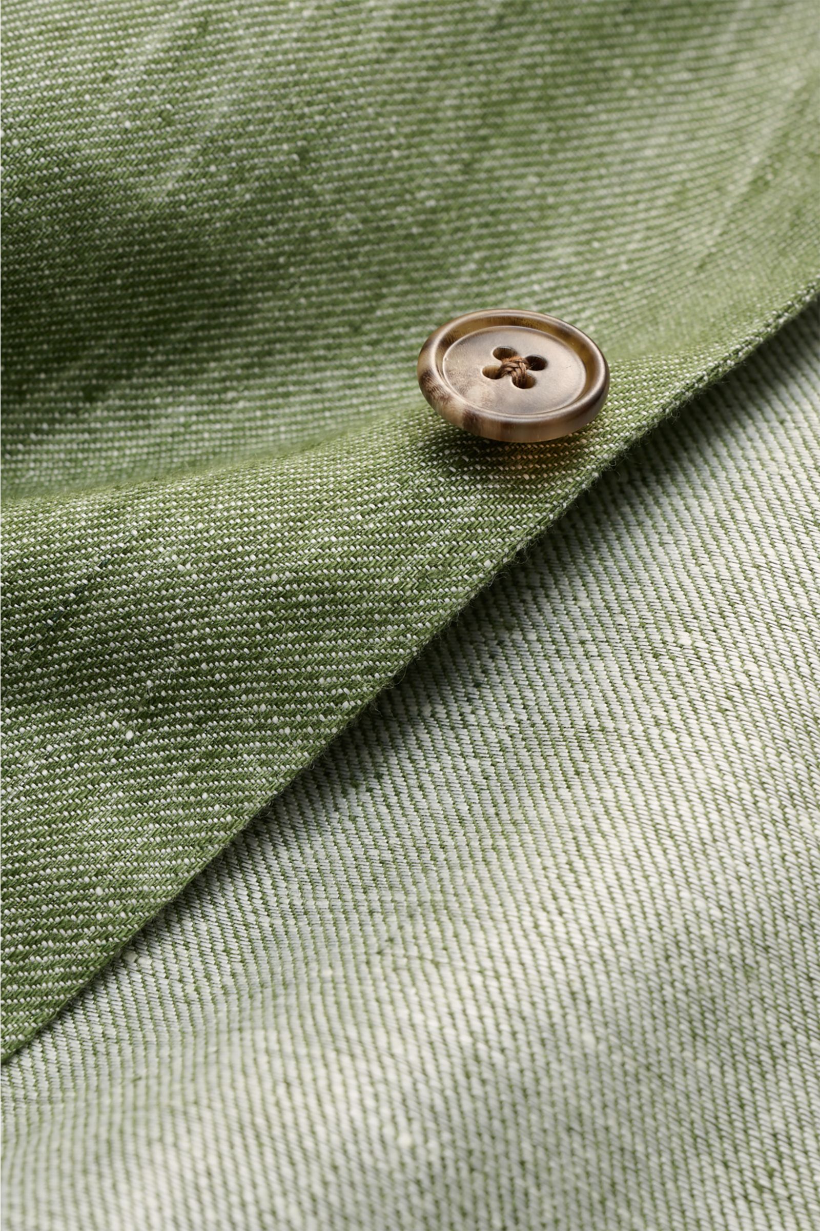 Nahaufnahme des Belvest Leinensakko grün meliert mit melierter Optik, Knopf und sommerlichem Leinenstoff aus schräger Perspektive.