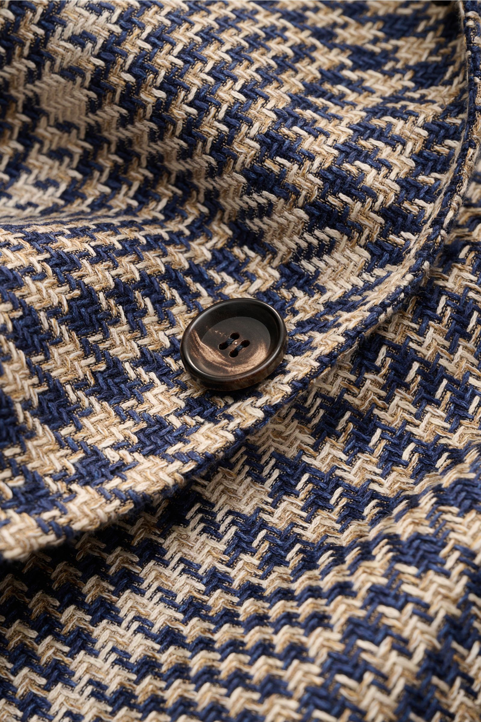 Close-up front detail of the button and fabric texture of the Stile Latino Smart-casual jacket 'Vincenzo' navy/beige checked.

STILE LATINO presents luxury you can feel with its lightweight smart-casual jacket 'Vincenzo' in a fine silk blend. Buy it an