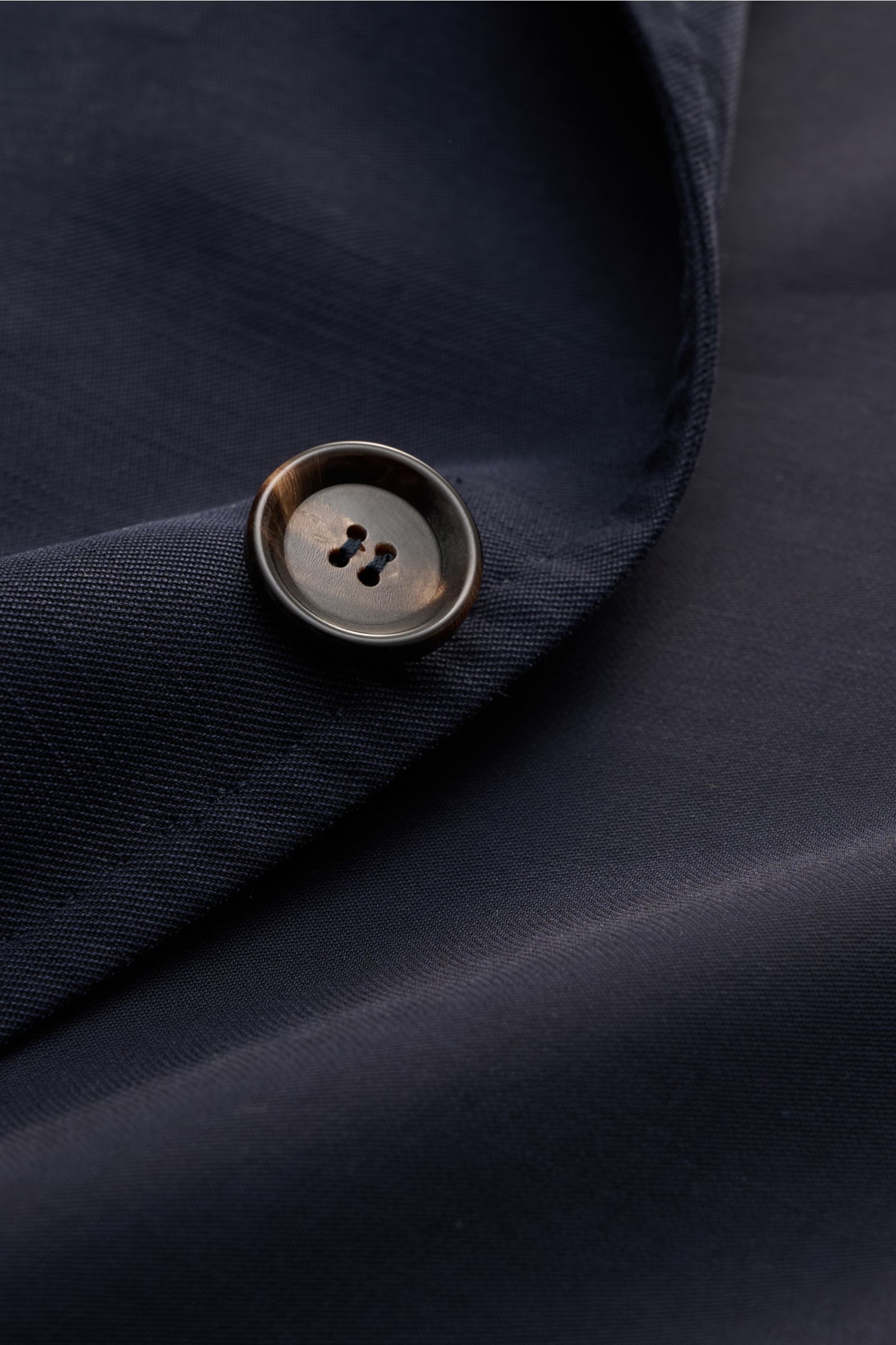 Close-up front detail of the button and fabric texture of the Sipario Smart-casual jacket 'Ginza' dark navy.

Description:  
Lightweight and stylish: The smart-casual jacket 'Ginza' by SIPARIO features a pared-down, unlined design in soft viscose – ide