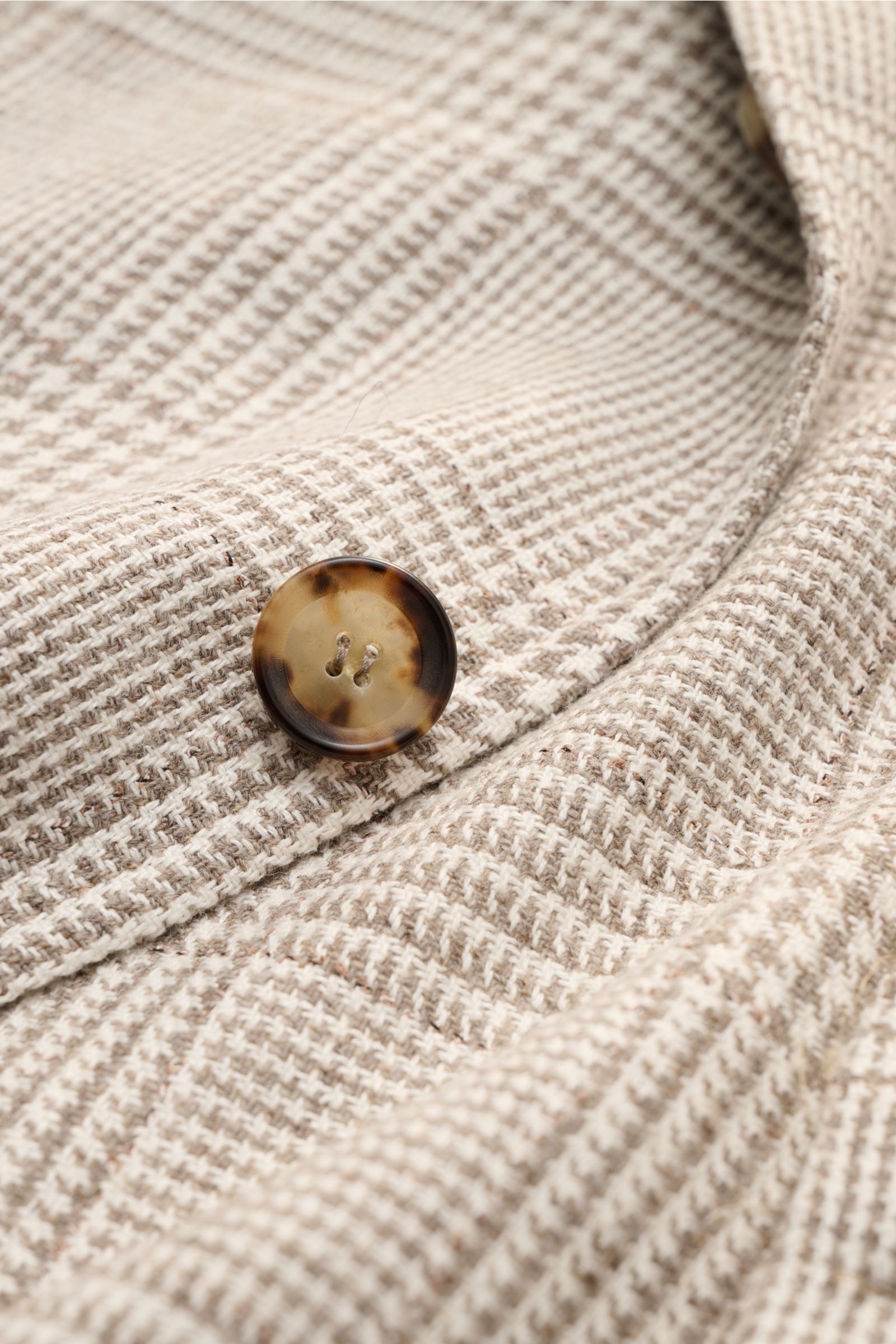Close-up front detail of the Sipario Smart-casual jacket 'Ginza' taupe/cream checked showing lightweight linen and silk blend fabric with classic glen check and a tortoiseshell button.

Lightweight and stylish: The smart-casual jacket 'Ginza' by SIPARI