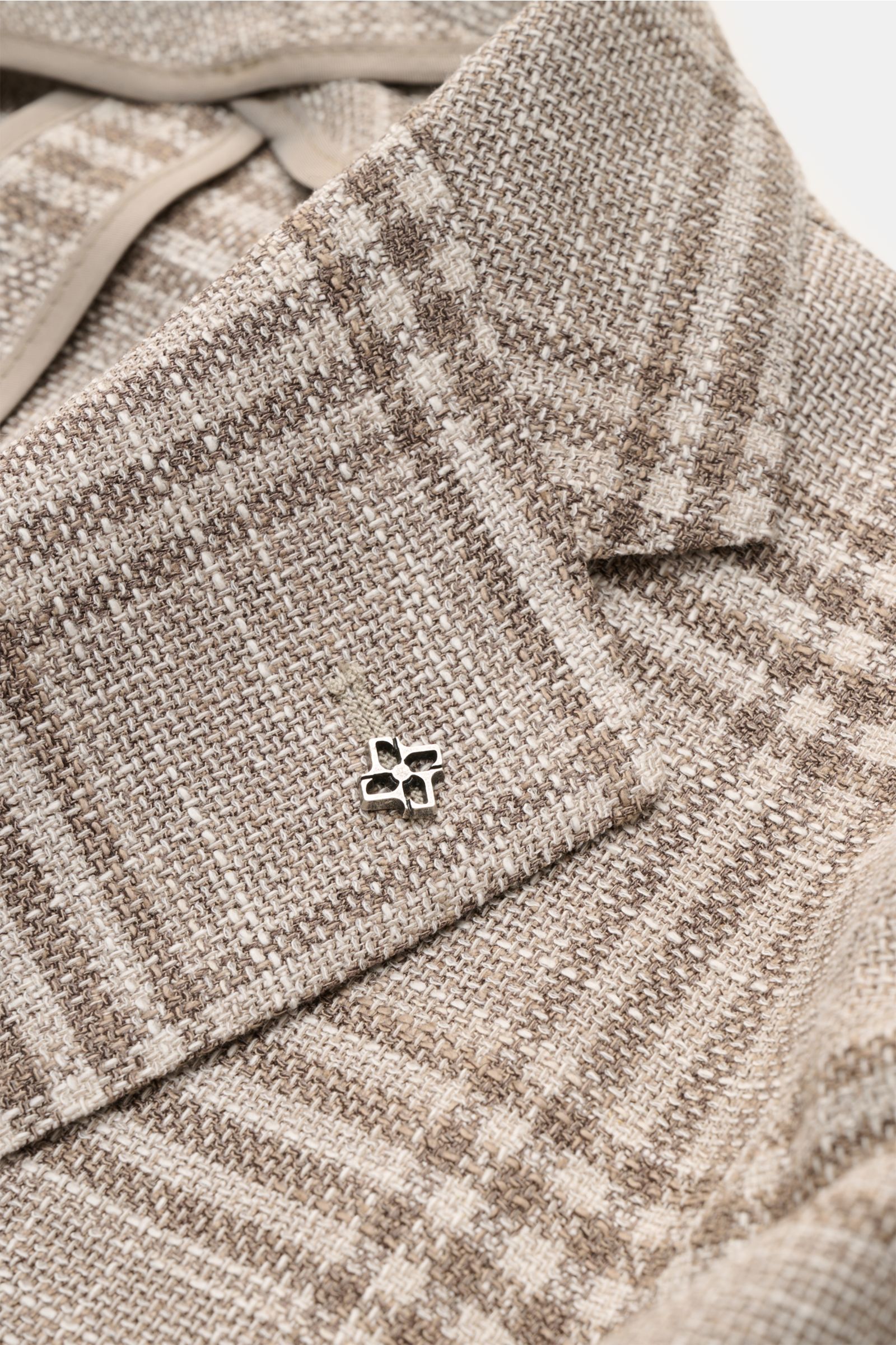 Close-up front view of the Tagliatore Smart-casual jacket 'Monte Carlo' beige/taupe checked, showing the textured checked fabric, step lapel with signature pin, and fine blend of virgin wool, cotton, and silk. The unconstructed finish and elasticated, sof