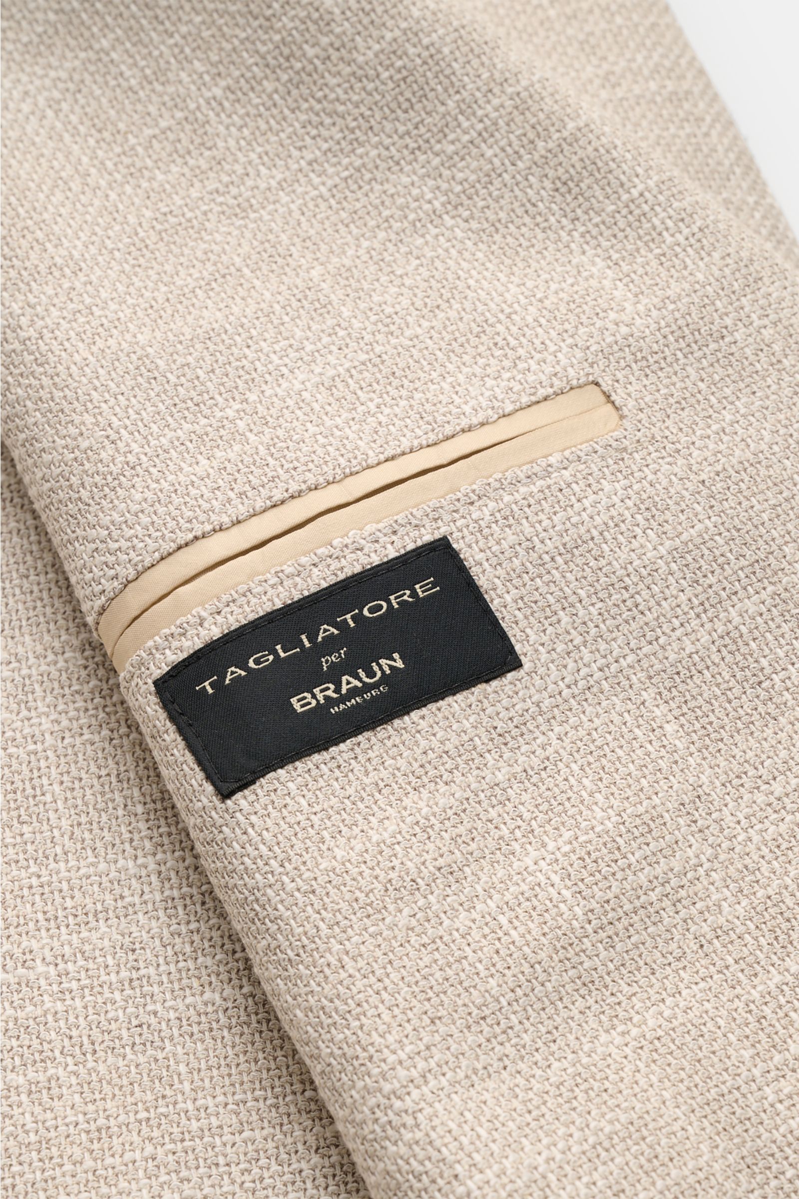 Close-up view of the beige mottled textured fabric and label of the Tagliatore Smart-casual jacket 'Monte Carlo,' showing unconstructed design.

The unconstructed finish in a fine blend of fabrics refined by effect yarn for a relaxed weave makes the sm