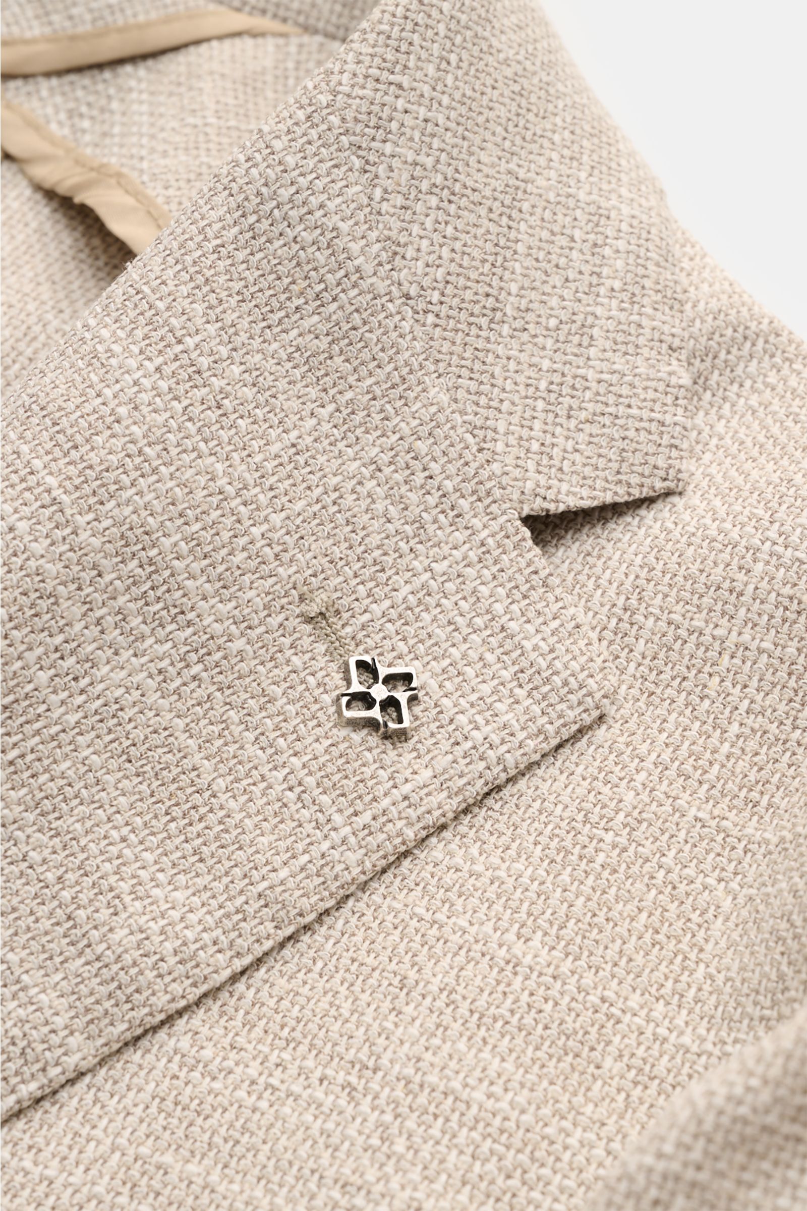 Close-up of the lapel and textured fabric of the Tagliatore Smart-casual jacket 'Monte Carlo' beige mottled, photographed from above, featuring a signature pin on the step lapel. 

The unconstructed finish in a fine blend of fabrics refined by effect y