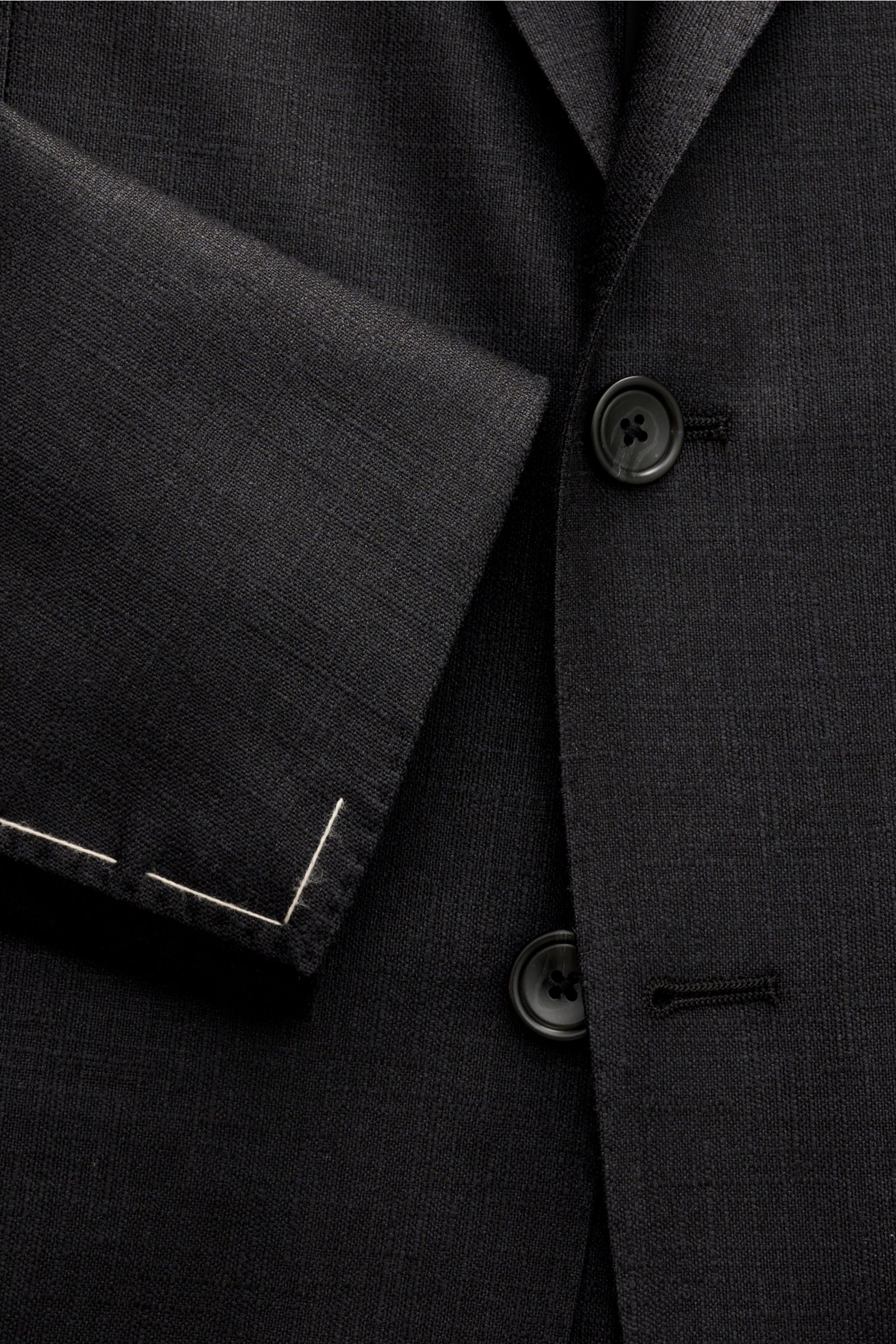 Close-up front view of the Tagliatore Smart-casual jacket 'Monte Carlo' black, showing slim fit, two-button style, step lapel, signature pin, breast pocket, patch hip pockets, unfinished sleeve cuffs, and fine textured silk and virgin wool blend fabric. 
