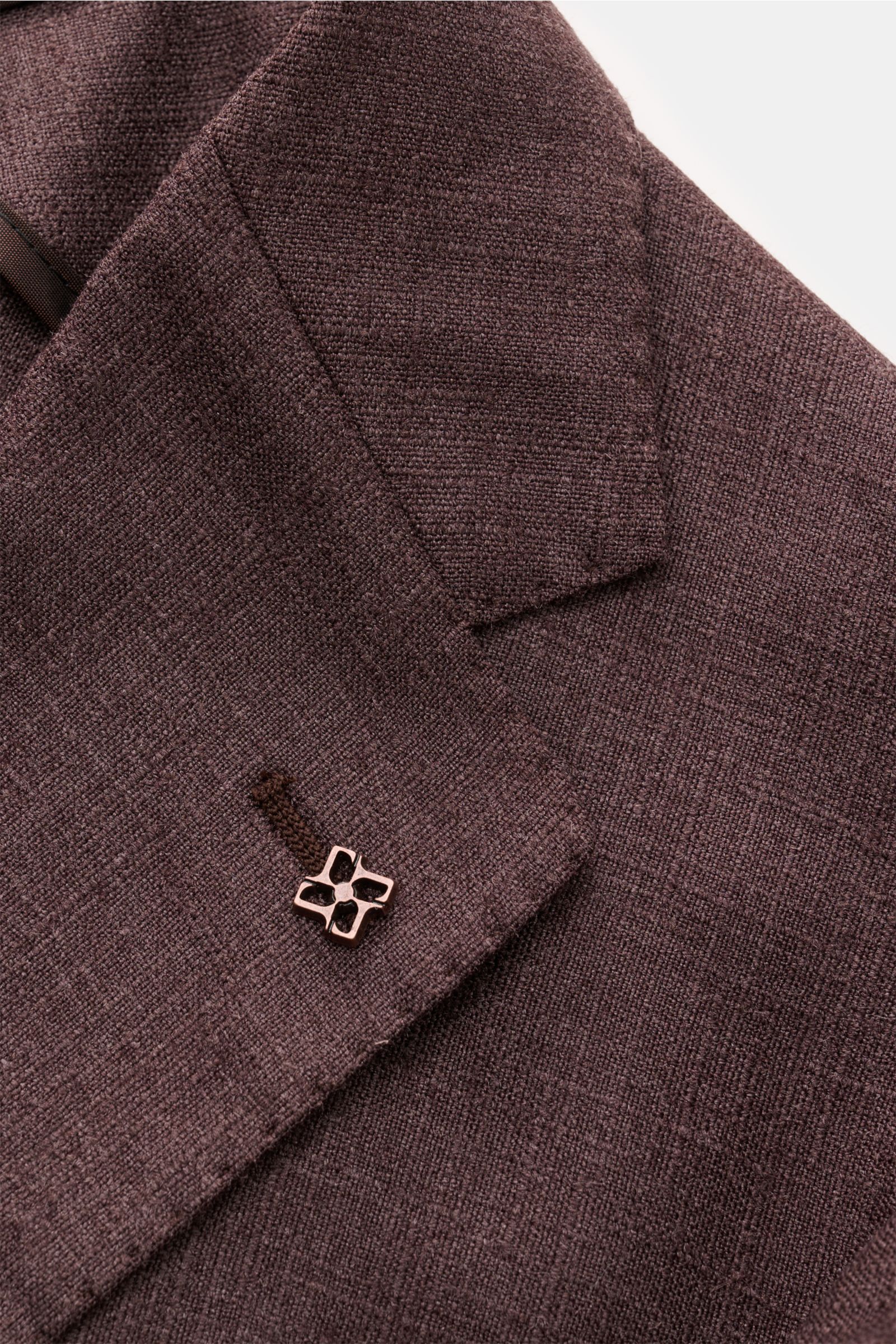 Nahaufnahme des dunkelbraun melierten Tagliatore Sakko 'Monte Carlo' Revers mit markentypischem Pin, feinem Strukturgewebe aus Seide und Schurwolle.