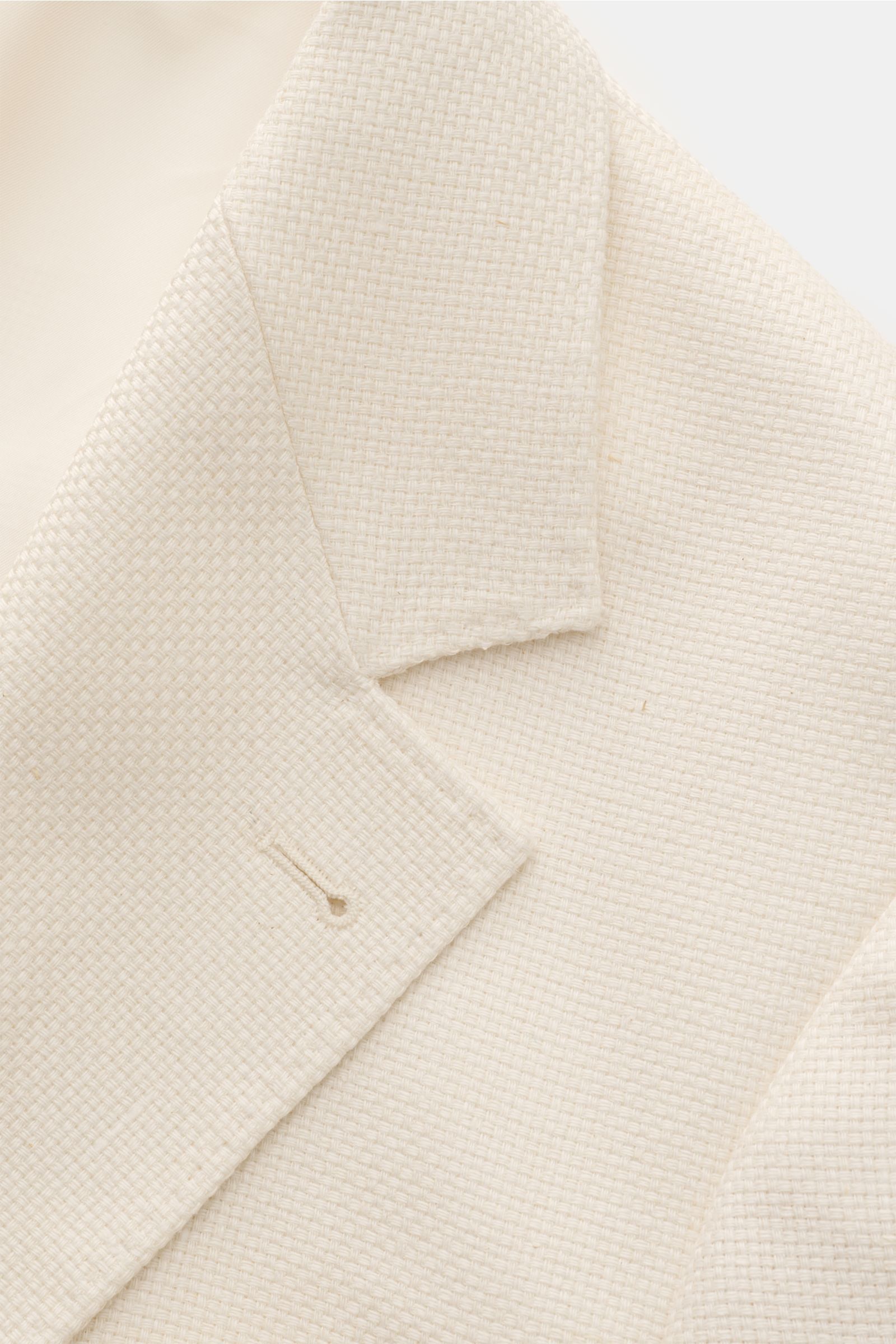 Brustnah fotografiertes Brunello Cucinelli Sakko creme mit Panama-Webstruktur, Slim Fit, fallendem Revers und drei Knöpfen.