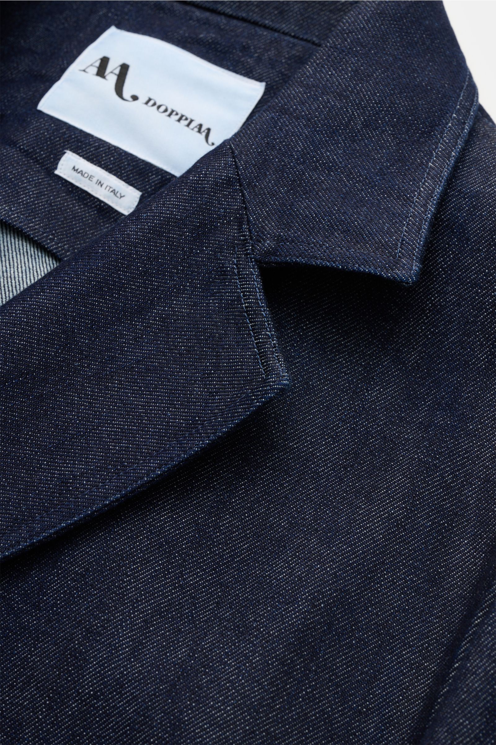 Close-up front view of the Doppiaa Denim jacket 'Aansonia' navy showing the step lapel and denim texture made of pure cotton, slim fit, double-breasted three-button style with patch hip pockets and an unconstructed design. A new casual interpretation of a