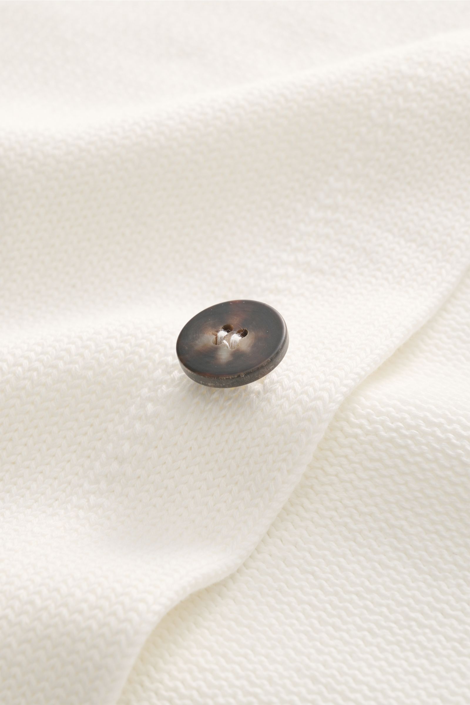 Close-up front view of the Doppiaa Cardigan 'Aalviero' off-white shows its medium-fine cotton knit texture and a dark button.

Description: Timeless elegance for the transitional season: The 'Aalviero' cardigan by DOPPIAA combines the features of a sma