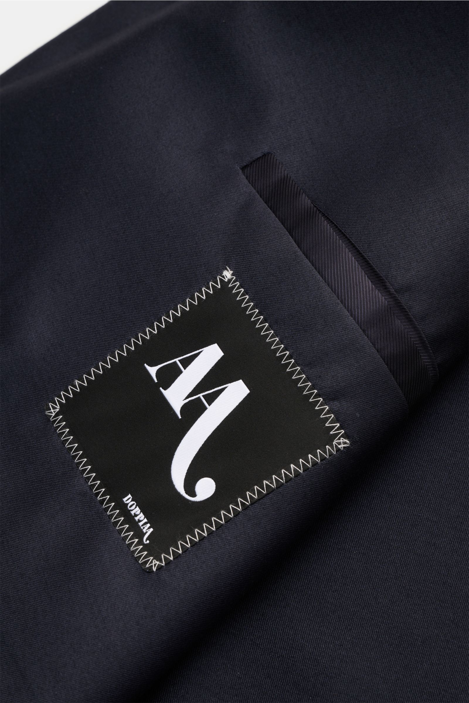Nahaufnahme des Doppiaa Sakkos 'Aanversa' navy, detailreich fotografiert von oben, zeigt edlen Wolle-Seide-Twill mit Label, klassischem Design und feinem Glanz.