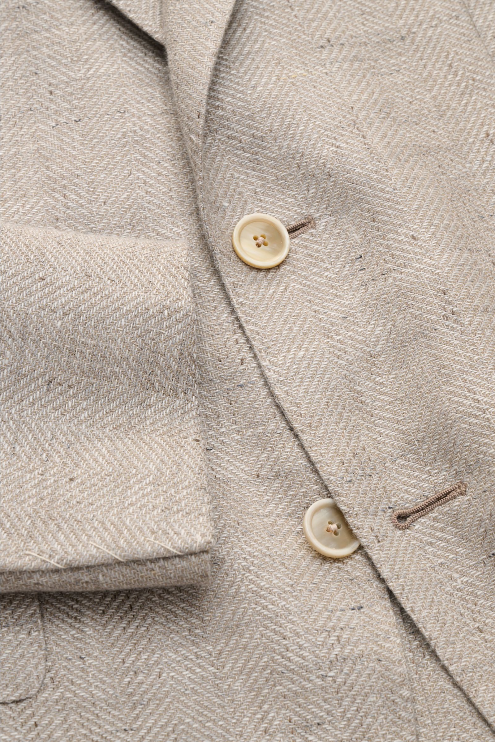 Close-up of Caruso Smart-casual jacket 'Aida' beige mottled showing herringbone texture, buttons, and sleeve cuff from a top-front angle.

In the smart-casual jacket 'Aida', CARUSO combines smart style with fabric in the natural materials linen and woo