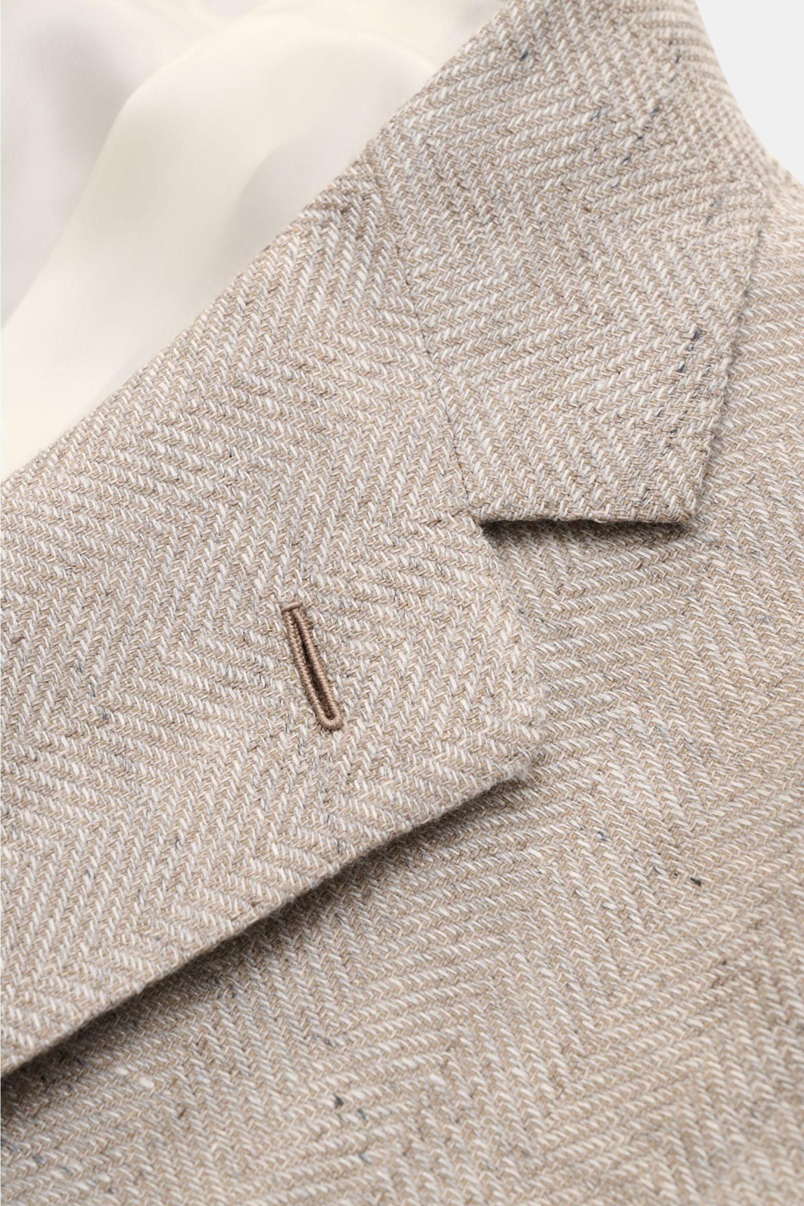 Close-up front-side view of Caruso Smart-casual jacket 'Aida' beige mottled showing herringbone texture and step lapel.

In the smart-casual jacket 'Aida', CARUSO combines smart style with fabric in the natural materials linen and wool – and the herrin