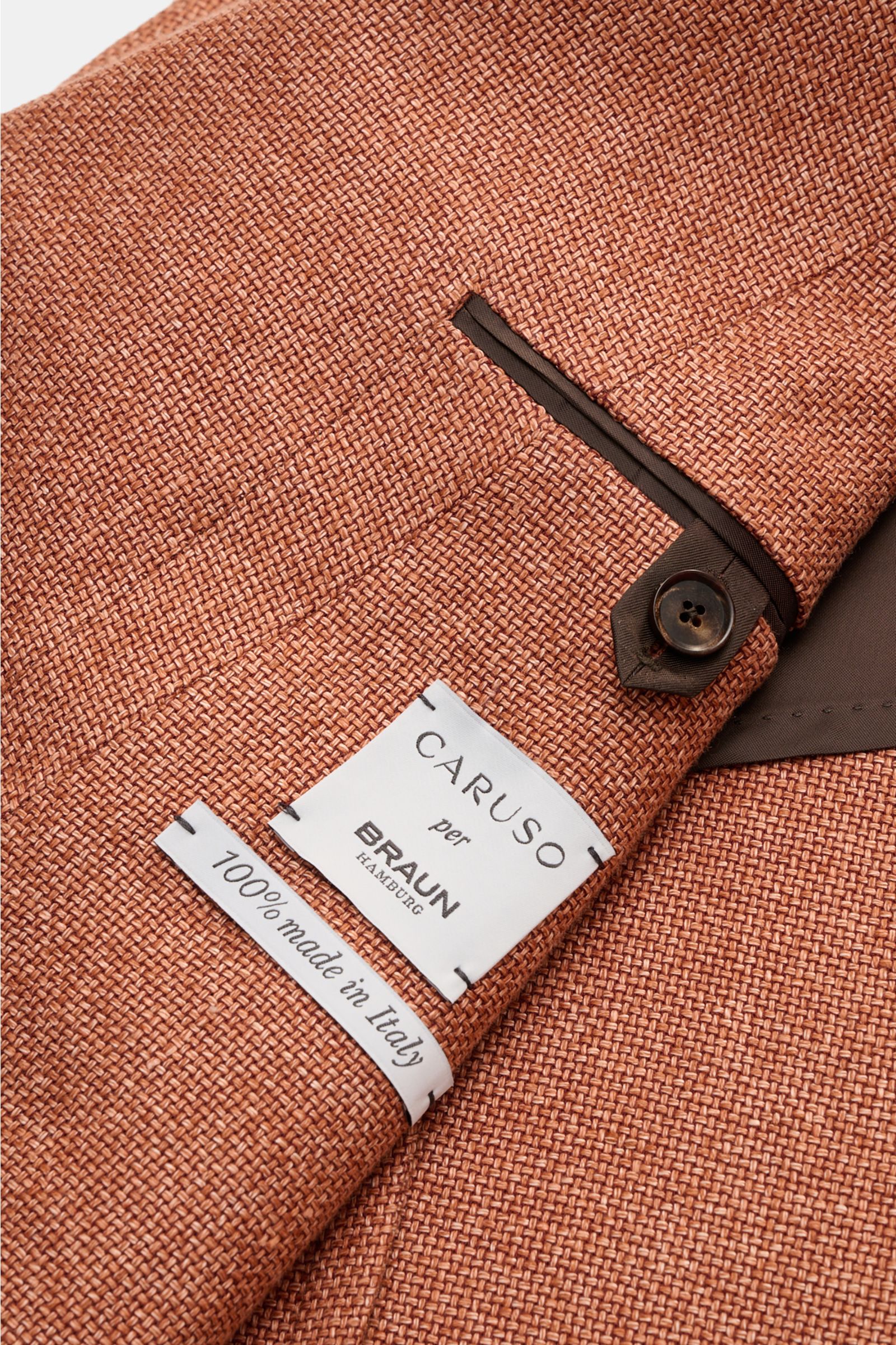 Caruso Sakko 'Aida' rostbraun meliert, Nahaufnahme der griffigen Hanf-Wolle Webstruktur, steigendem Revers und Drei-Knopf-Ärmel mit Label.