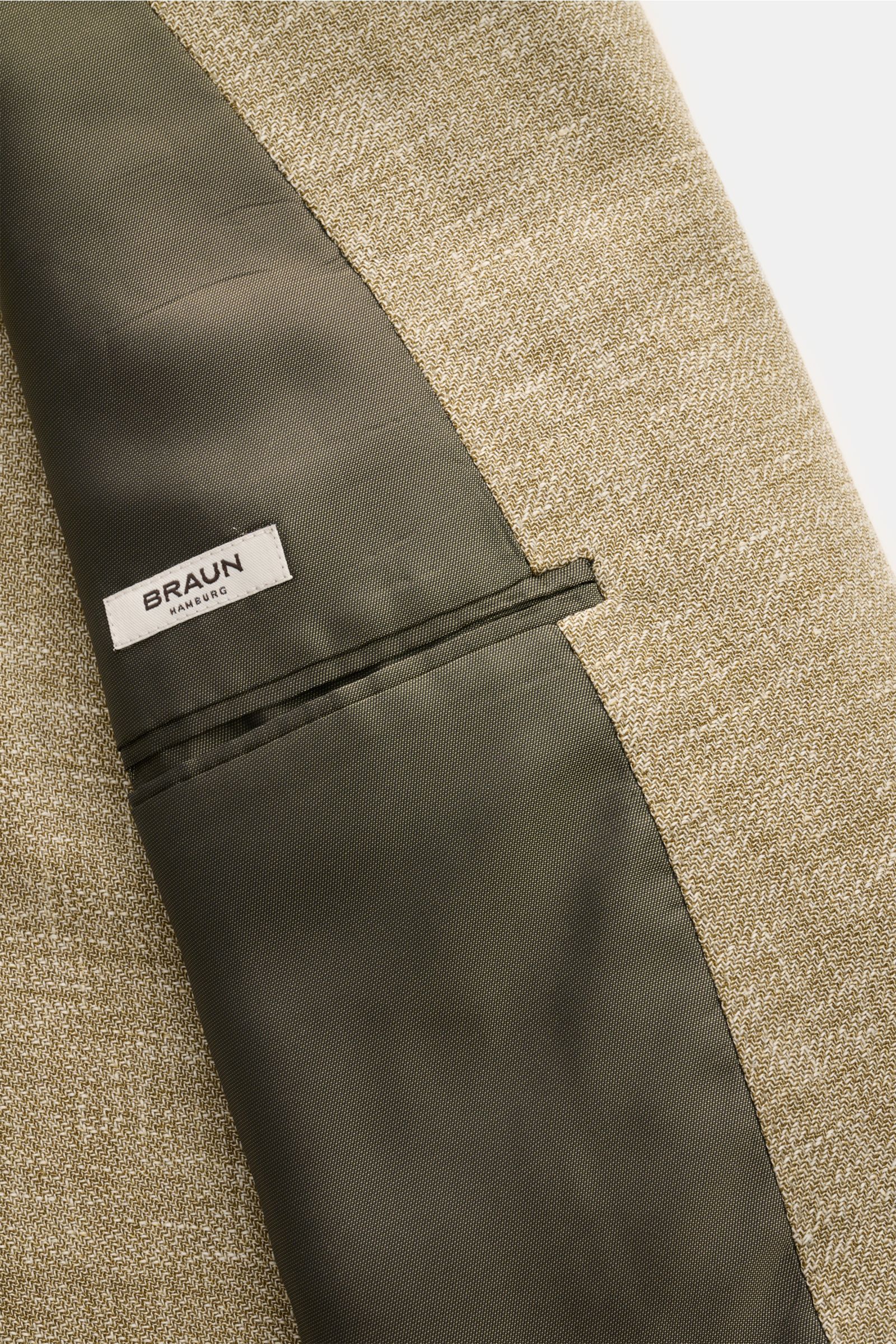 Nahaufnahme des Zegna Sakko oliv meliert mit feinem Strukturgewebe, innen grün gefüttert, Slim Fit, zwei Knöpfe, drei Innentaschen.