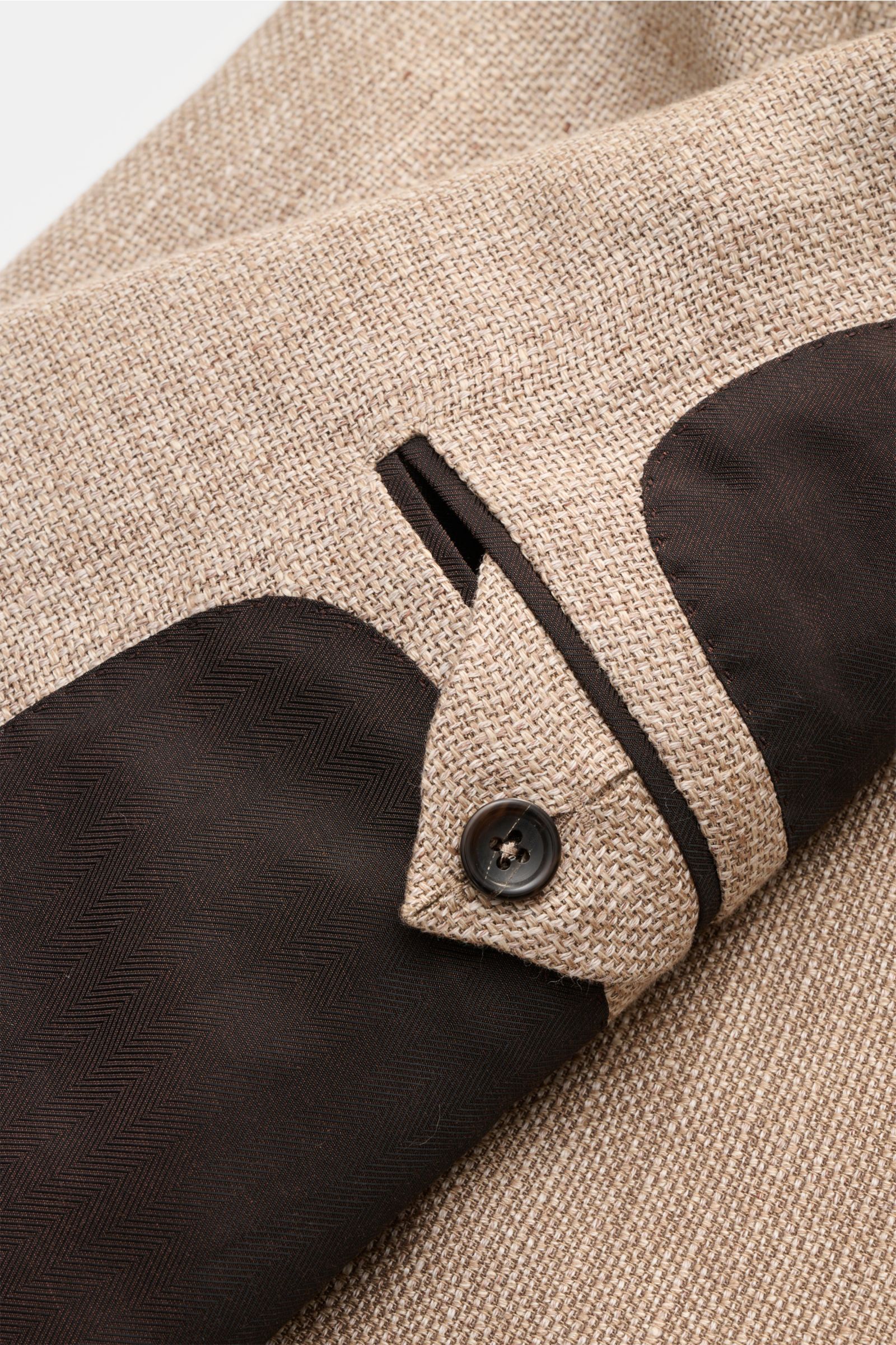 Close-up view of the sleeve cuff of the Zegna Smart-casual jacket taupe mottled, highlighting the fine textured linen, wool, and silk fabric blend with dark patch elbow detail and button.

Hot days are guaranteed to be enjoyable in this smart-casual ja