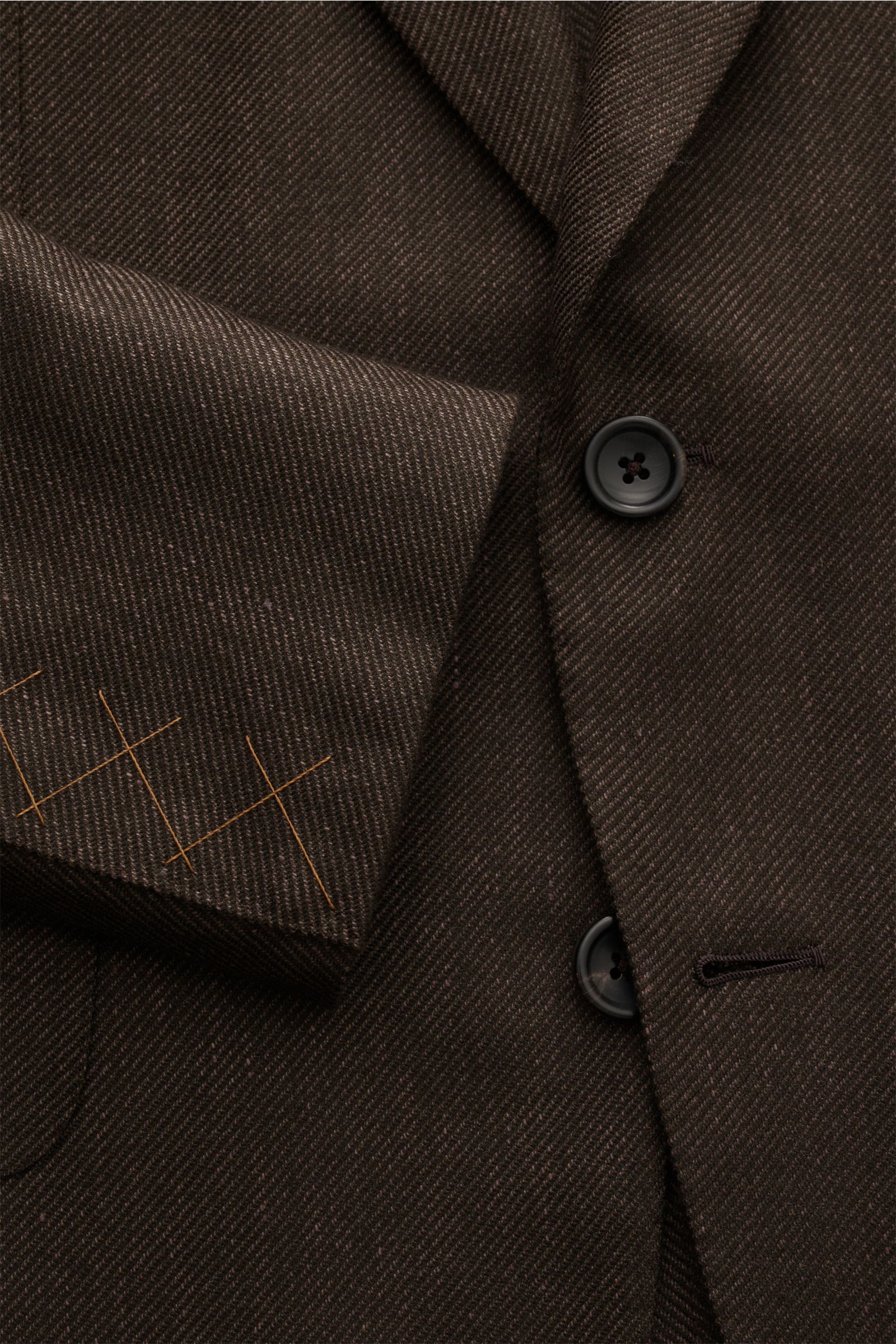 Nahaufnahme aus schräger Perspektive des dunkelbraunen Zegna Sakkos mit feinem Webmuster, zwei Knöpfen, fallendem Revers und weichem Griff.