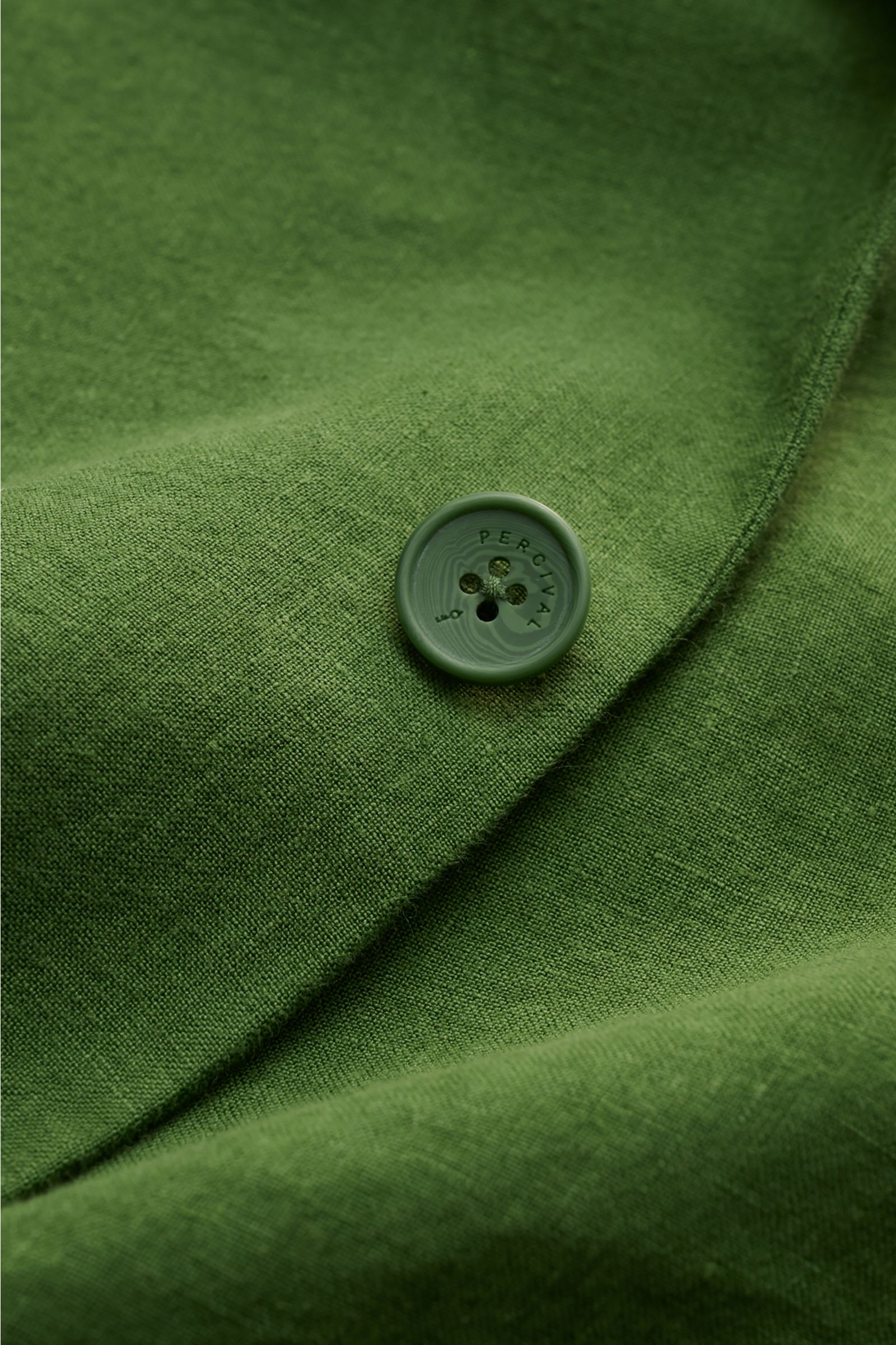 Close-up front view of the green Percival Smart-casual jacket 'Tailored Linen' showing textured linen-cotton fabric and a branded button. Combines texture and everyday suitability: This versatile smart-casual jacket by PERCIVAL combines maximum comfort