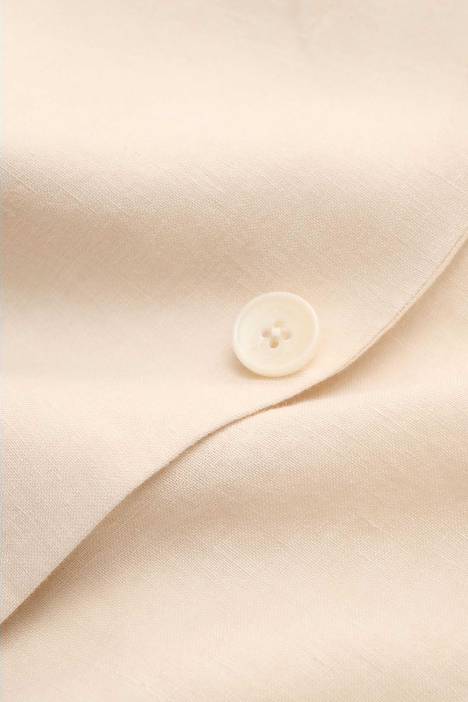Nahaufnahme des cremefarbenen Percival Sakko 'Tailored Linen' mit feiner Leinen-Baumwoll-Struktur und Knopf an Ärmelabschluss.