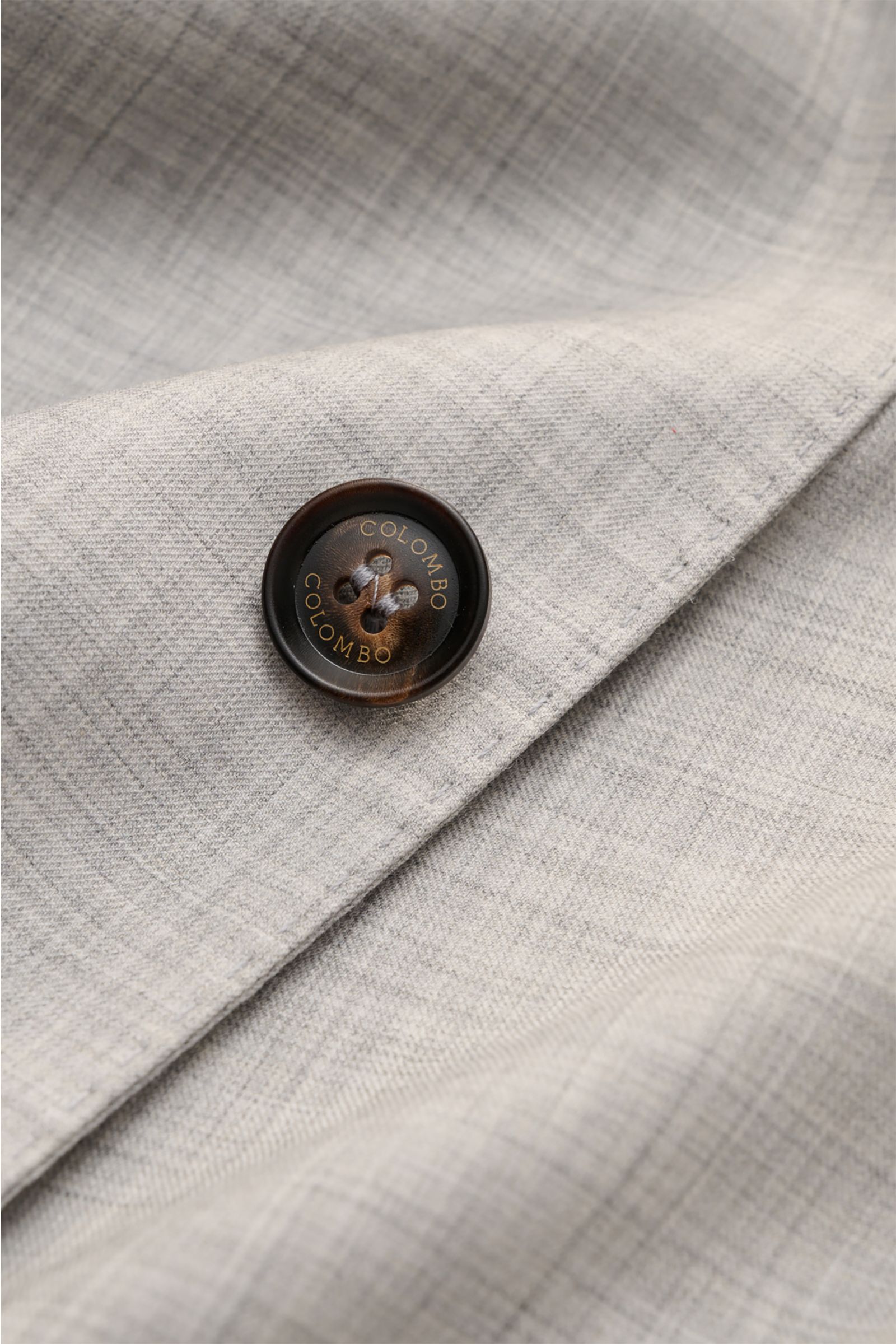 Close-up angled view of the Colombo Cashmere jacket 'Robert' light grey mottled fabric and brown button with COLOMBO engraving.

Description: Combed cashmere 4.0 is the lightest cashmere fabric in the world: The summery smart-casual jacket 'Robert' fro
