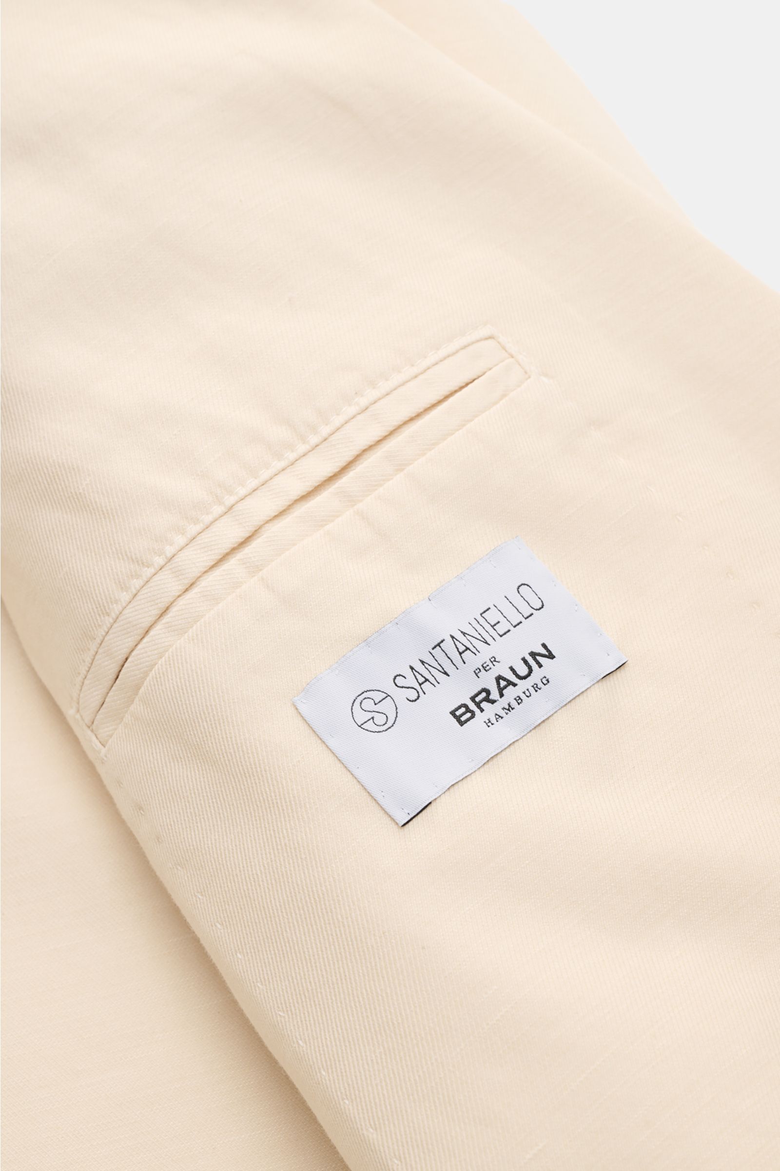 Nahaufnahme des Santaniello Sakko creme von innen, zeigt die Innentasche mit SANTANIELLO per BRAUN Hamburg Label, modernes Tailoring, weicher Griff, Slim Fit, Unconstructed Design.
