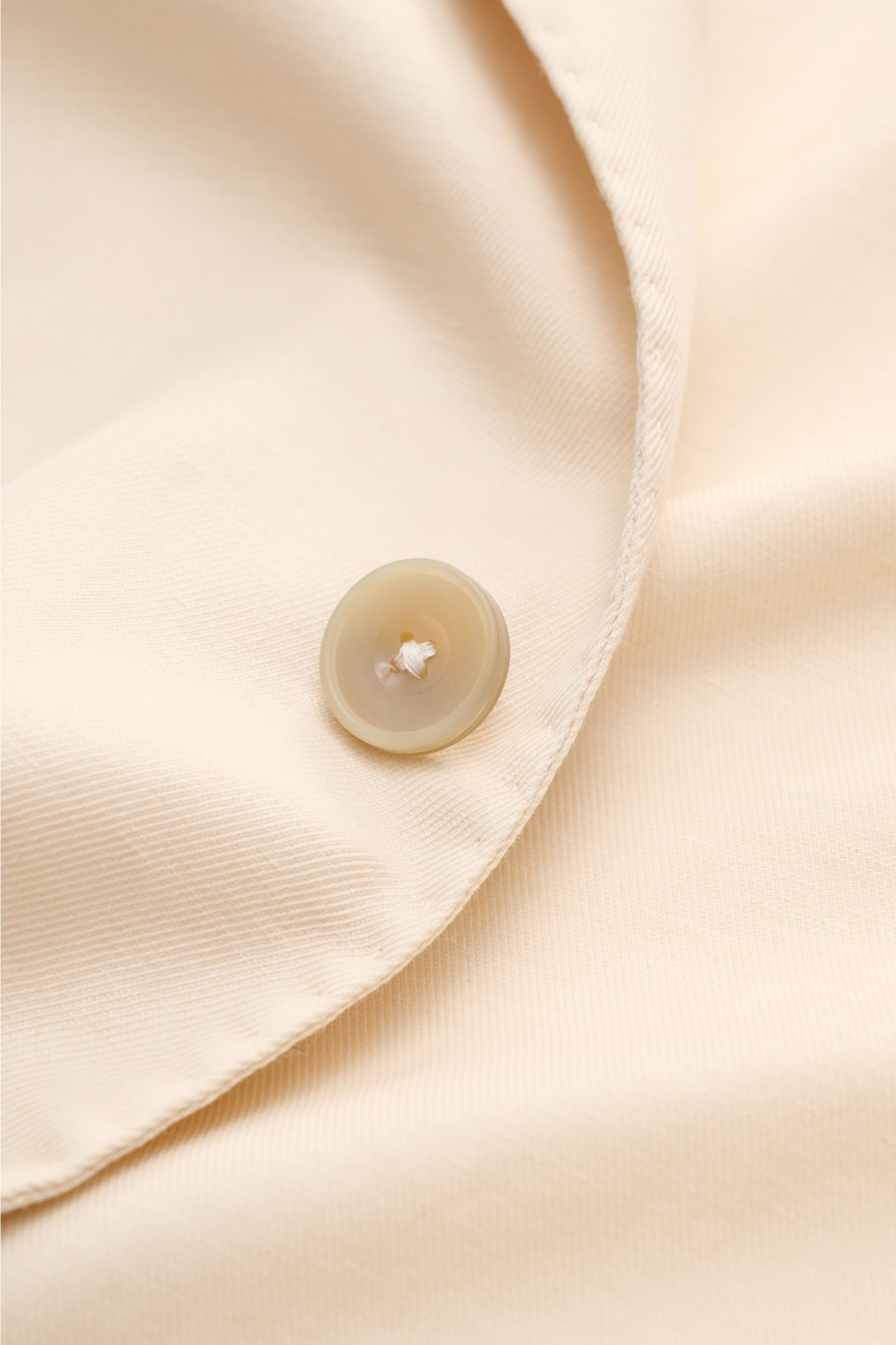 Nahaufnahme des Santaniello Sakko creme mit Fokus auf Knopf und fallendes Revers, modernes Tailoring aus Baumwolle, Leinen, Mohair.