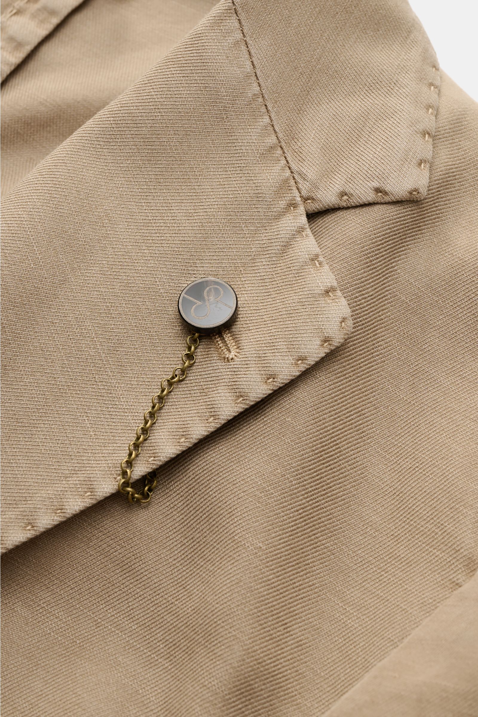 Nahaufnahme des fallenden Revers mit Label-Pin am Santaniello Sakko taupe, gefertigt aus Baumwolle, Leinen und Mohair.