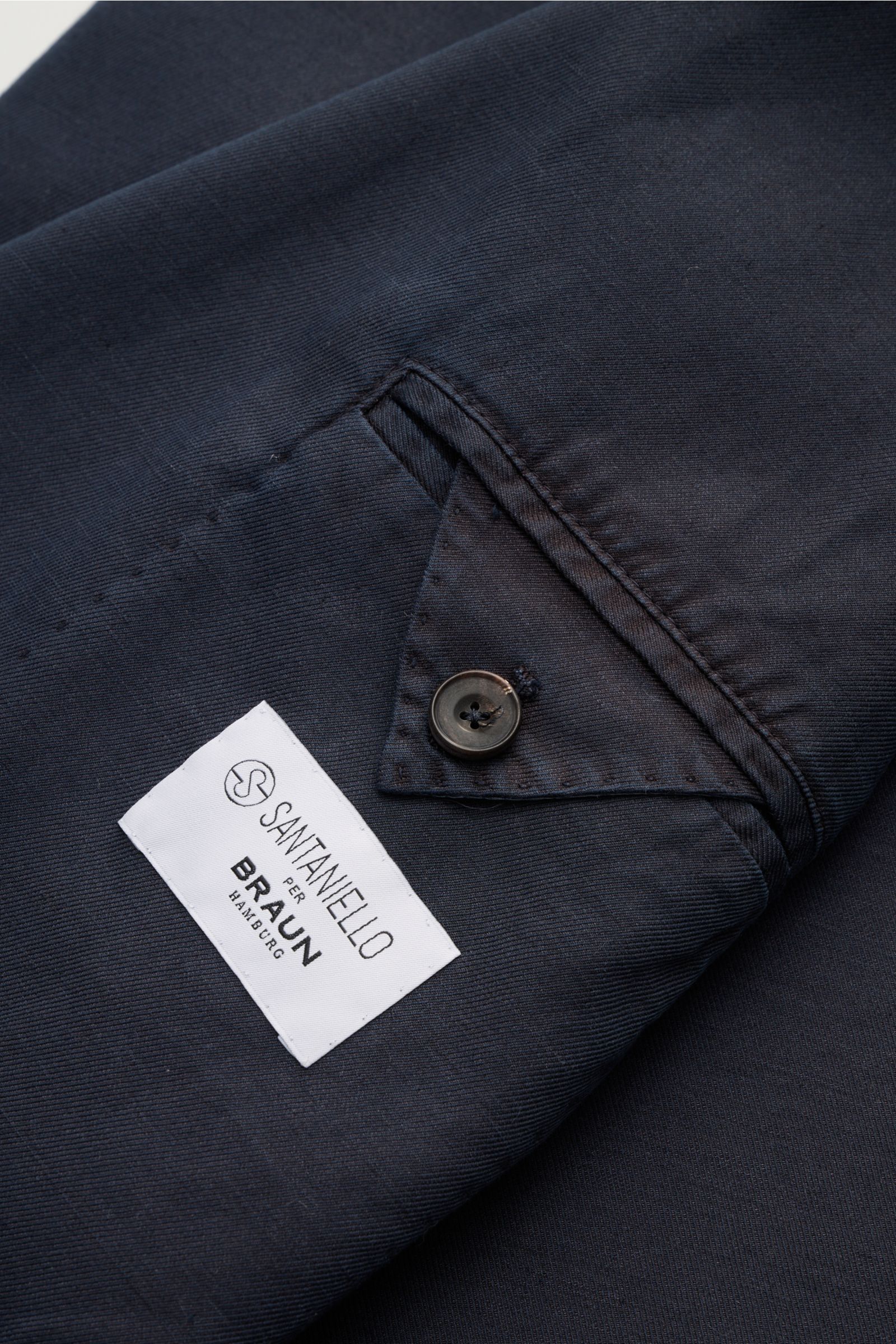 Close-up of Santaniello Smart-casual jacket navy showing the sleeve button and label from a top-down perspective. Modern tailoring for the transitional period: This smart-casual jacket by SANTANIELLO enhances numerous spring looks with its relaxed silhoue