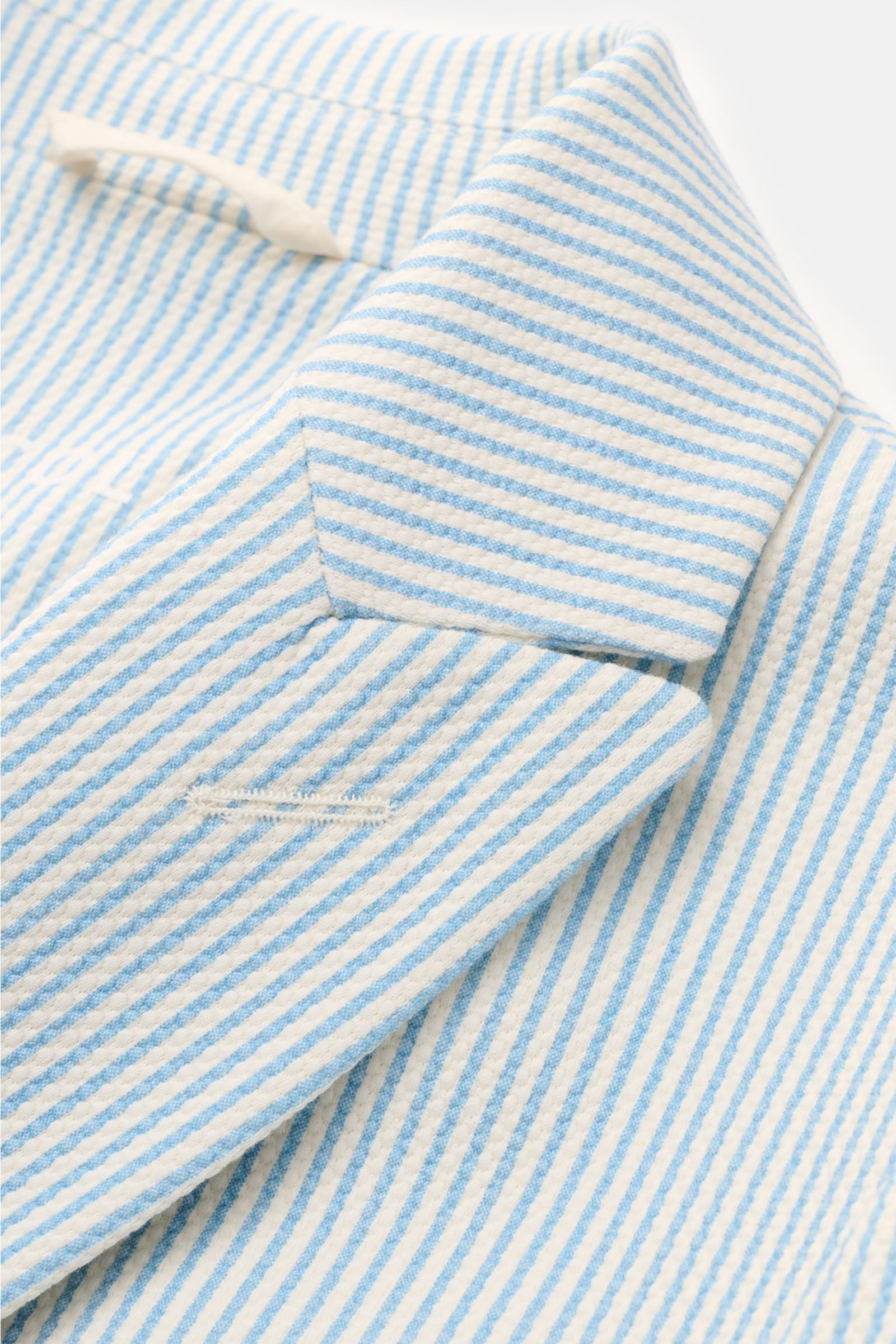 Nahaufnahme des Circolo 1901 Jersey-Sakkos weiß/hellblau gestreift, mit fallendem Revers und klassischem Streifenmuster aus elastischer Baumwolle.