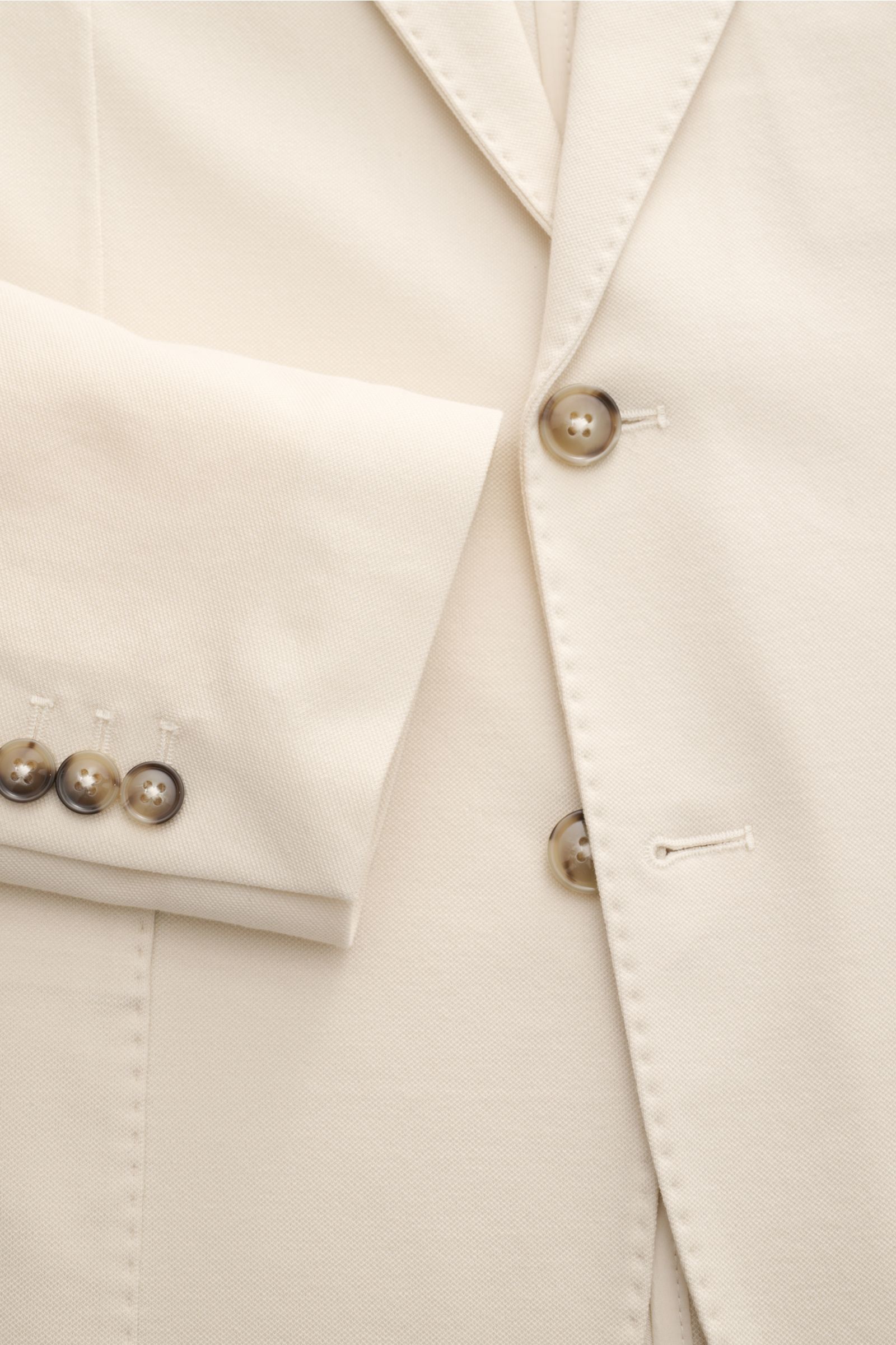 Nahaufnahme des Circolo 1901 Piqué Sakko sand aus elastischem Baumwoll-Piqué, Slim Fit, taillierter Zwei-Knopf-Stil, fallendes Revers, Ärmel mit Knöpfen, halb gefüttert, fotografiert aus seitlicher Perspektive.