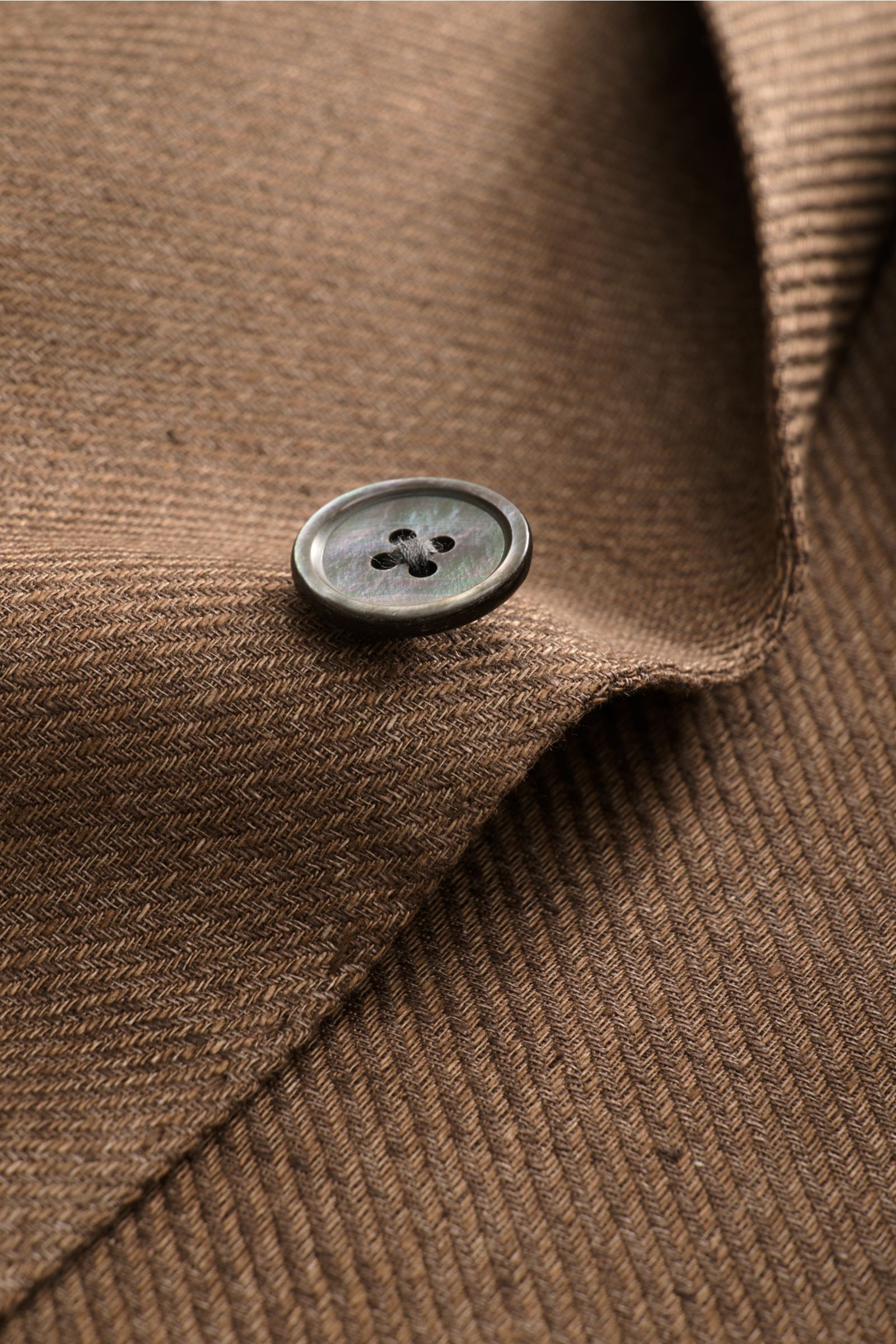 Close-up front-side view of the button and brown textured linen fabric of the Windsor Smart-casual jacket 'Giorno' brown mottled.

British elegance with summery lightness: The 'Giorno' unconstructed smart-casual jacket by WINDSOR, crafted from lightwei