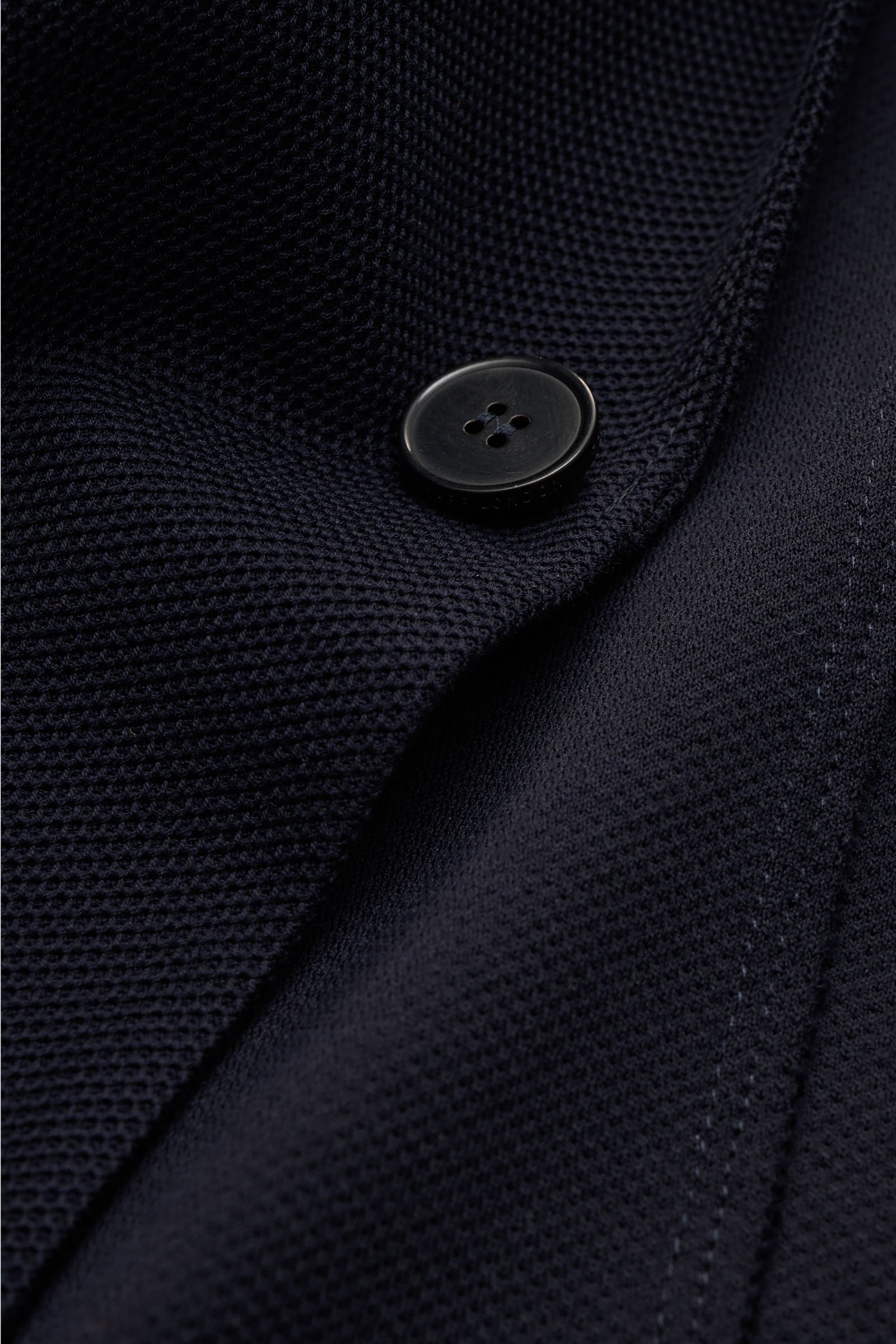 Close-up front detail of Harris Wharf London Blazer navy showing fine waffle texture, single black button, and stitching from a top-down perspective. Lightweight blazer from HARRIS WHARF: This model with a fine but distinctive waffle texture is made of