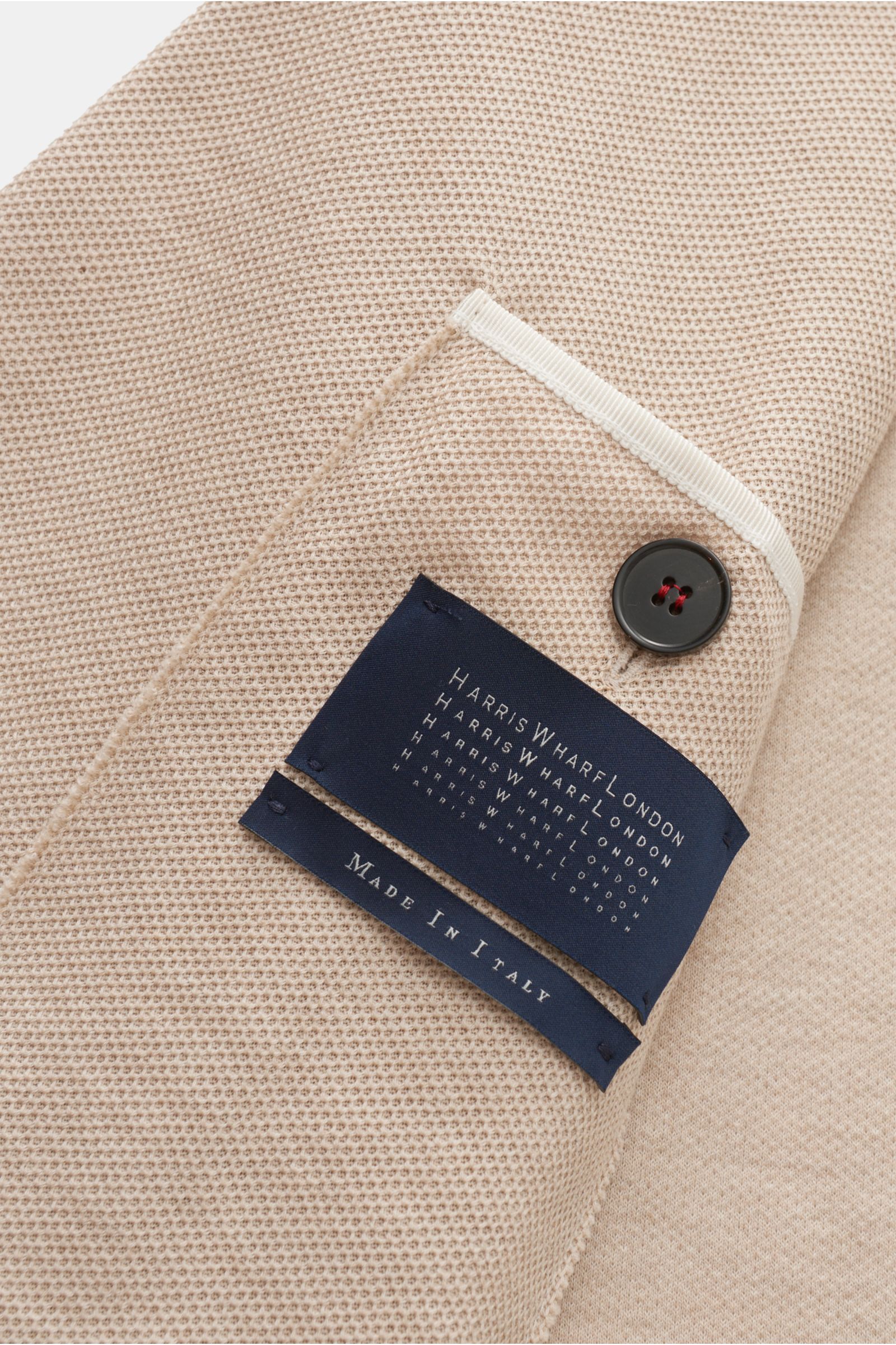 Nahaufnahme des Harris Wharf London Blazer beige, fotografiert von innen mit Fokus auf feine Waffelstruktur, Loro Piana Baumwolle, Button und Etikett.