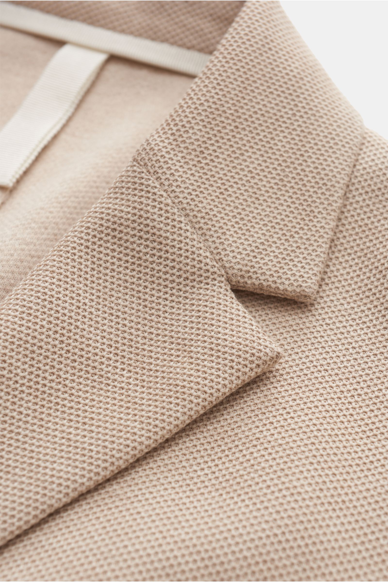 Nahaufnahme eines beige Harris Wharf London Blazers mit feiner Waffelstruktur, fallendem Revers und tailliertem Zwei-Knopf-Stil aus Loro Piana Baumwolle.