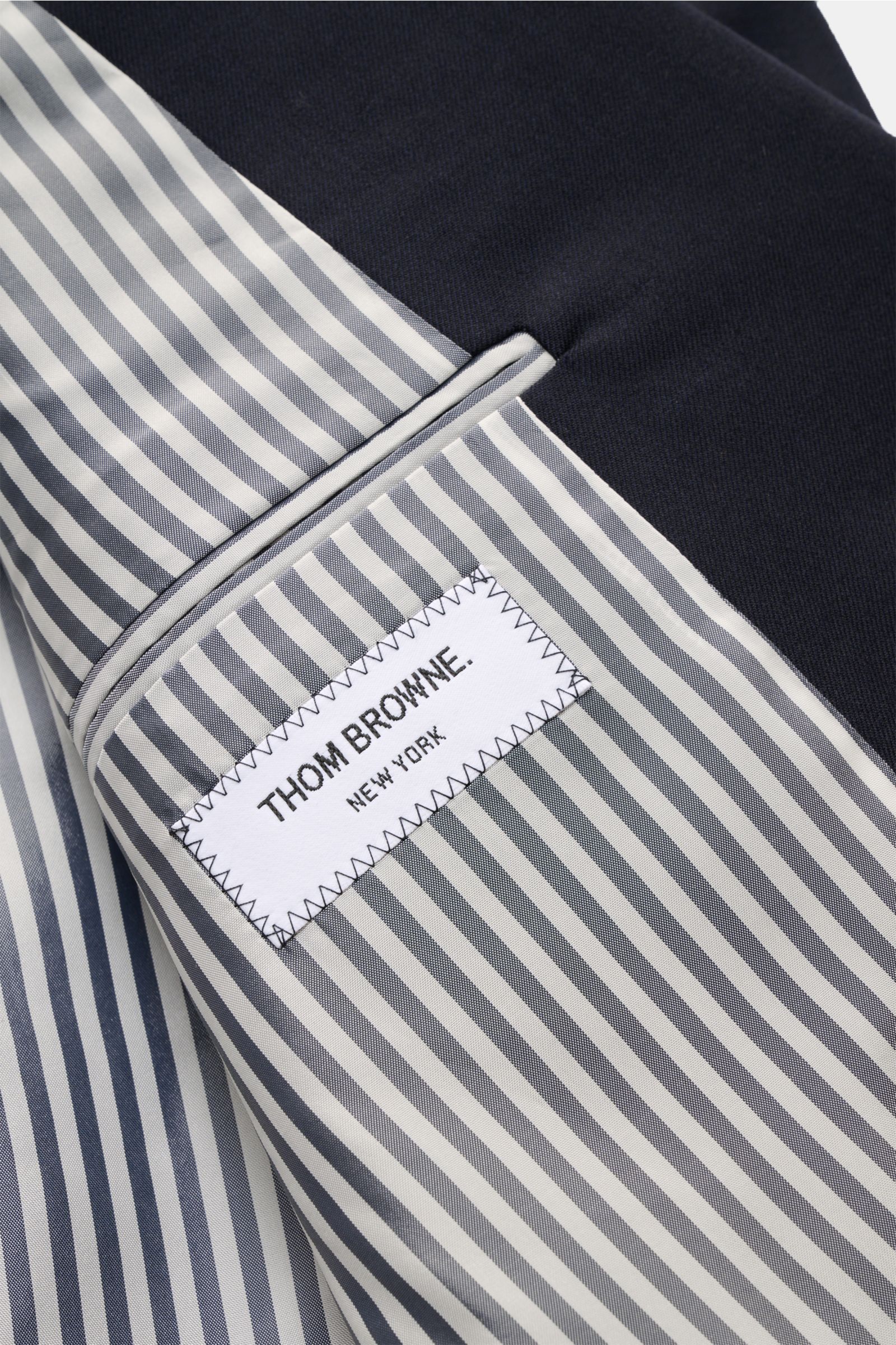 Innenansicht mit gestreiftem Futter und Thom Browne Label des maritim monochromen Thom Browne Sakko navy aus reiner Wolle.