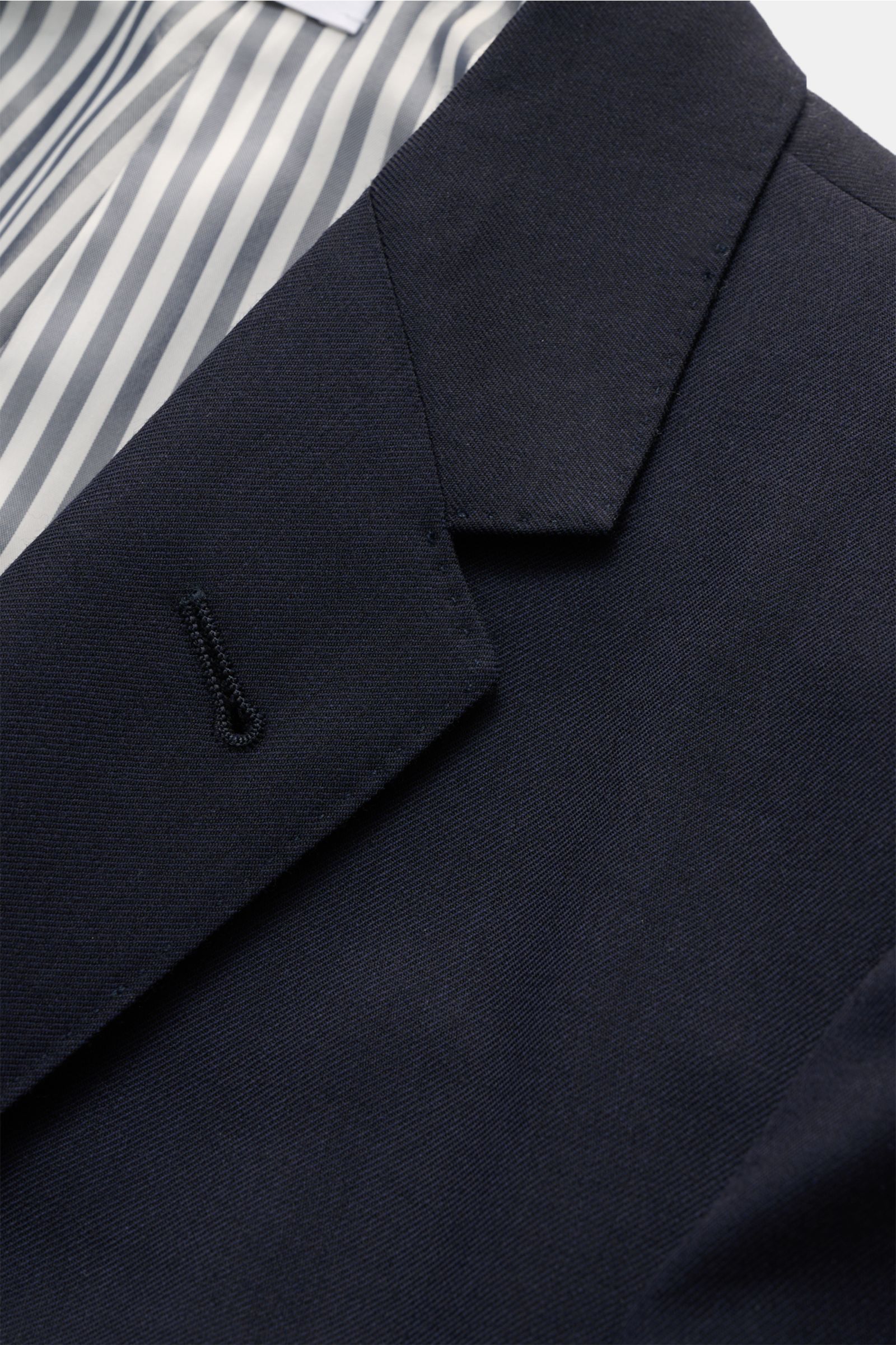 Nahaufnahme des fallenden Revers und gestreiften Innenfutters vom maritim monochromen Thom Browne Sakko navy aus reiner Wolle.