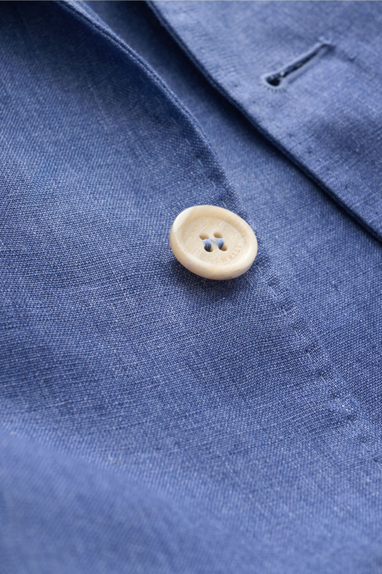 Close-up front angle of Brunello Cucinelli Leinensakko graublau meliert showing melierte denim-look linen fabric and cream button with stitching details. Leicht, edel und mit unverwechselbarer Präsenz: Dieses melierte Drei-Knopf-Sakko von BRUNELLO CUCINEL