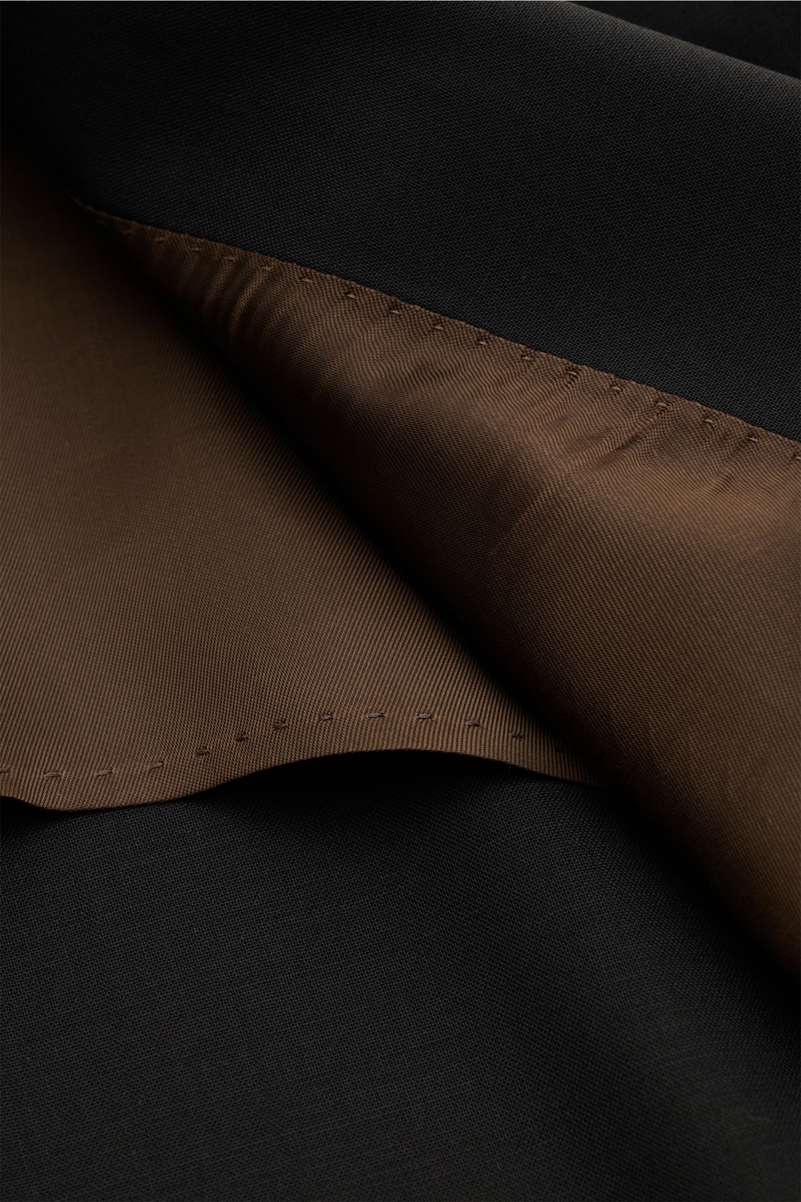 Nahaufnahme der Innenansicht des Windsor Sakko 'Sono' schwarz, zeigt braunes Innenfutter und feines, elastisches Wollgewebe.