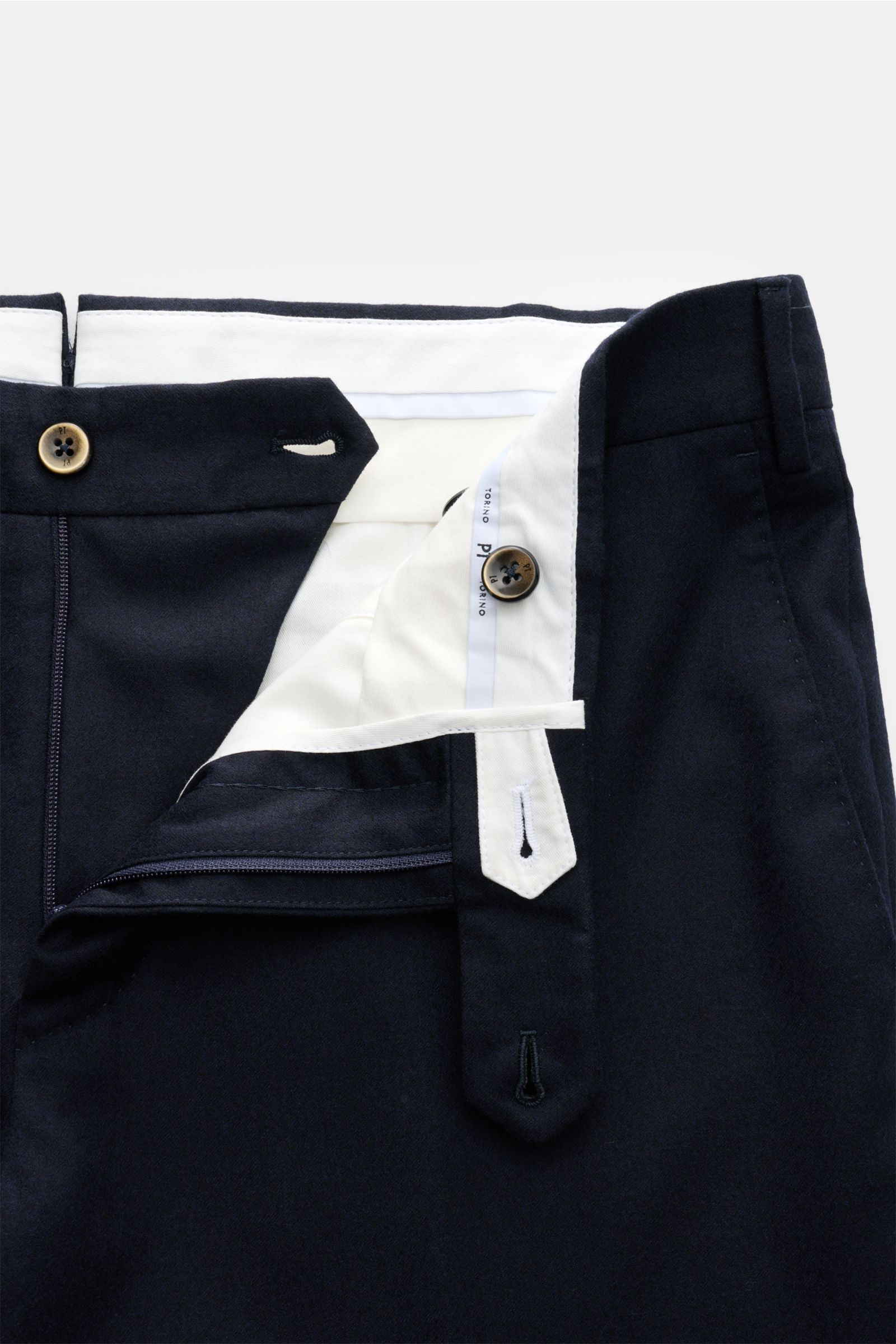 Close-up front view of the PT Torino Wool trousers 'Slim Fit' dark navy waistband and zipper area, showing fine wool fleece with slight stretch, soft lightweight fabric, zip and waist buttons, and detailed white inner lining. For these exclusive trousers,
