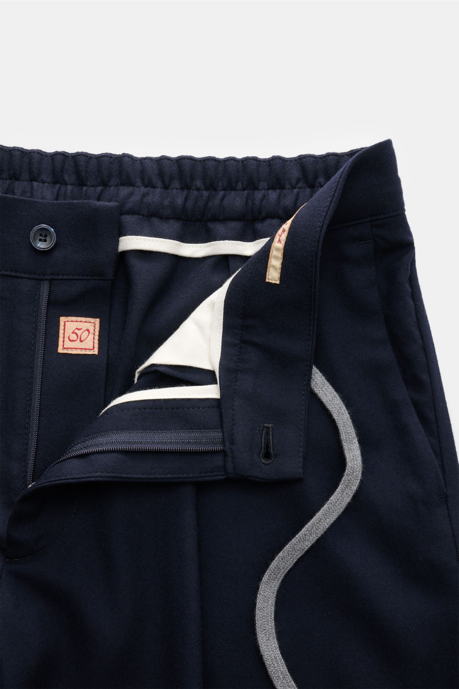 Close-up front view of Marco Pescarolo Woll-Jogpants 'Varenne' navy showing elastic waistband with drawstring, zipper, button, and detailed inner lining with size tag 50 and stitched features including French pockets and fixed hem cuffs. 